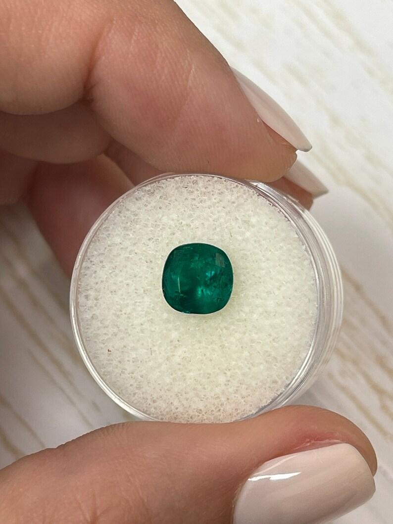 Stone: Emerald
Weight: 1.71-carats
Shape: Cushion Cut
Clarity: Transparent
Luster: Very Good
Color: Dark Muzo Green
Measurements: 7.68mm x 7.67mm x 5.30mm
Geographic Origin: Colombia
Treatment: Natural, Oiling

Comments: Due to their growth