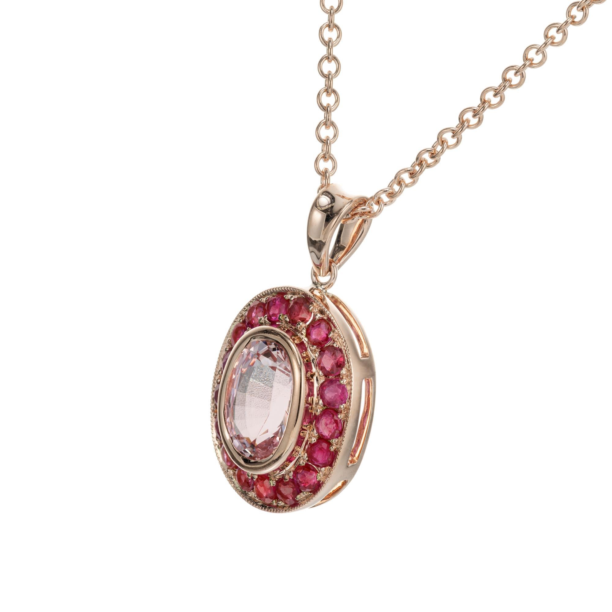 Oval soft light pink sapphire center stone, bezel set with a halo of 17 round bead set rubies.  On Peter's now famous pink gold scale of 1 to 10 with 10 as the deepest pink this scores an 8.  18 inch 14k rose gold chain.

1 oval pink sapphire
