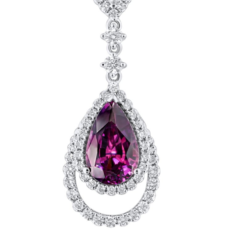 This beautiful pendant features a 1.72 carat pear shape rose pink sapphire, inside a halo of round diamonds, and within an additional frame of round white diamonds. An elegant dangle design is formed by two more round diamonds, and a decorated bail.