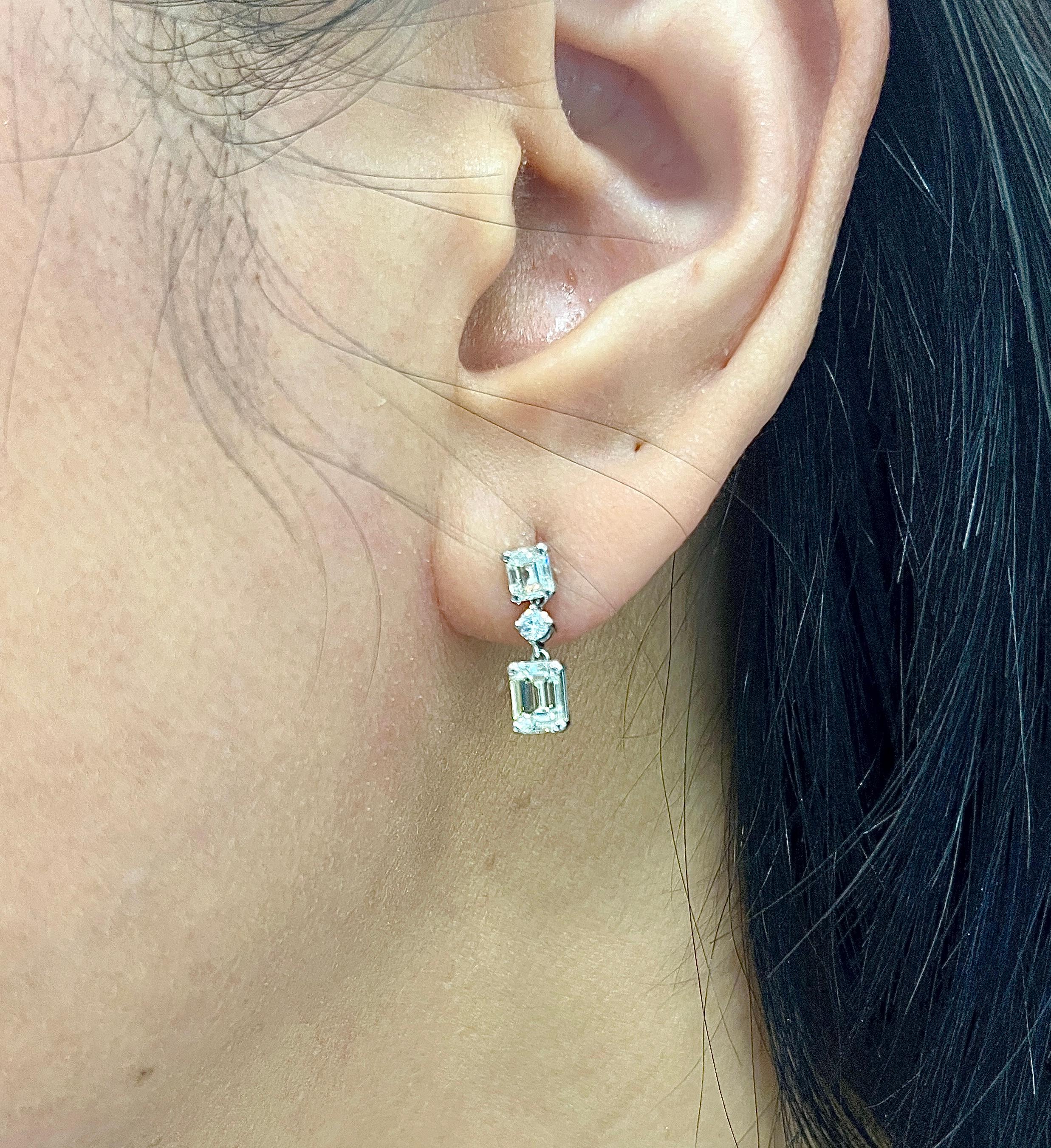 These stunning 1.72 ct emerald cut diamond dangle earrings feature 6 diamonds total with 2 round diamonds, all set in platinum. The diamonds are I to K in color, and VS1/VS2 in clarity. A great addition to any wardrobe. 