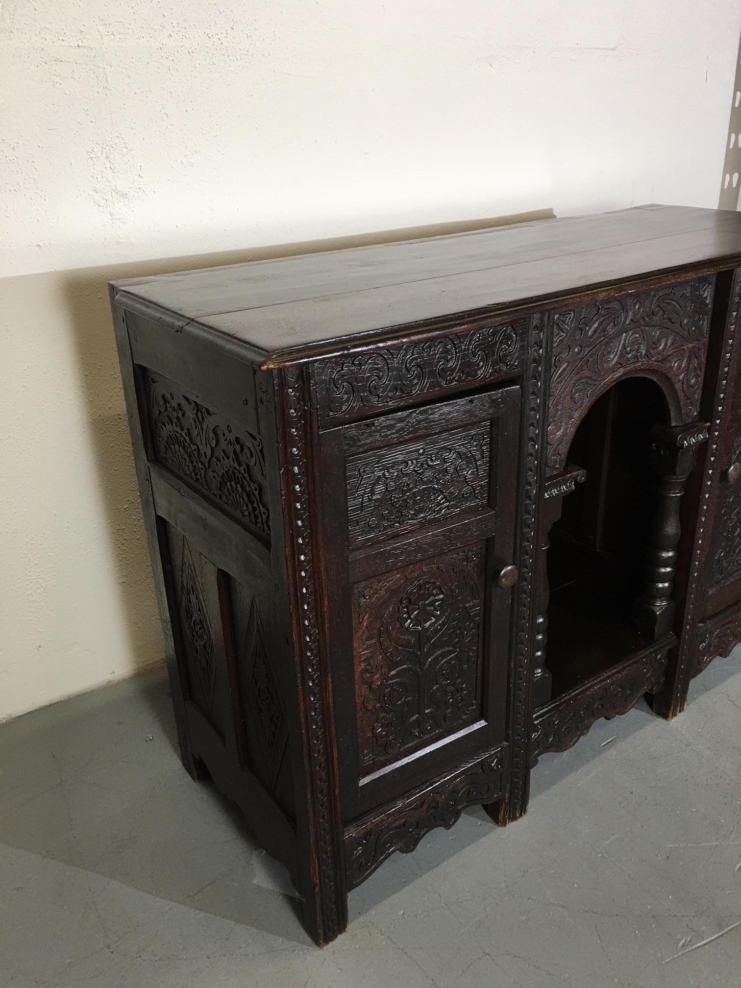 19th-century English sideboard. Carved doors on each side and a carved arch in the middle.