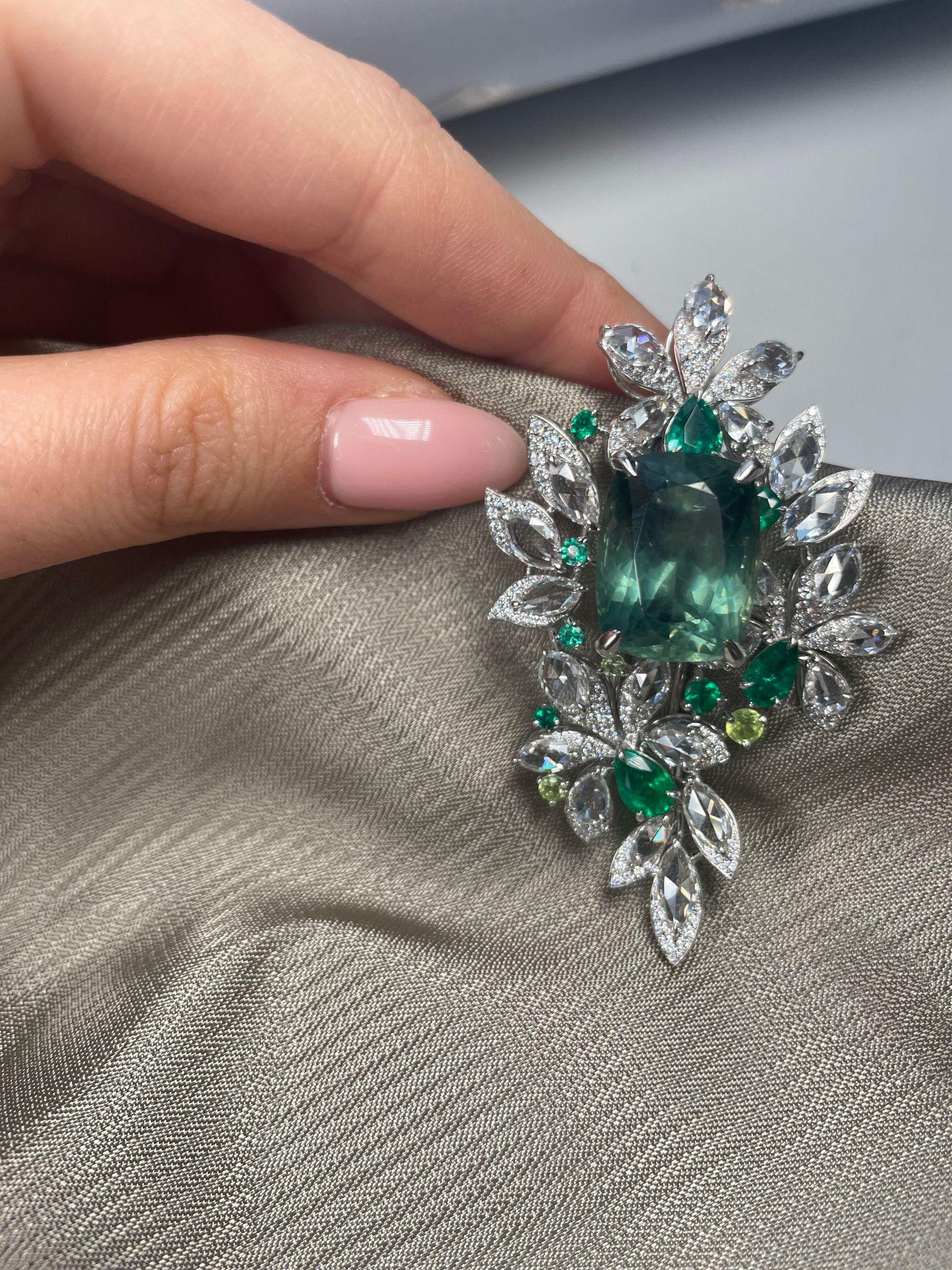 This exquisite piece features 17.26 Carat Green Apatite and 6.09 carat White Diamond Brooch, set in a floral motif. This unique and feminine brooch is crafted in luxurious 18K white gold and features 17 rose cut marquee-shaped diamonds weighing 4.32
