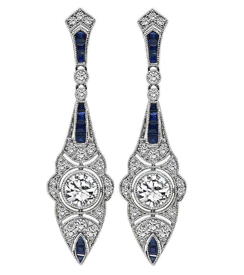 This is an elegant pair of 14k white gold earrings. The earrings feature sparkling round cut diamonds that weigh approximately 1.72ct. The color of these diamonds is H with VS clarity. The diamonds are accentuated by lovely sapphires that weigh