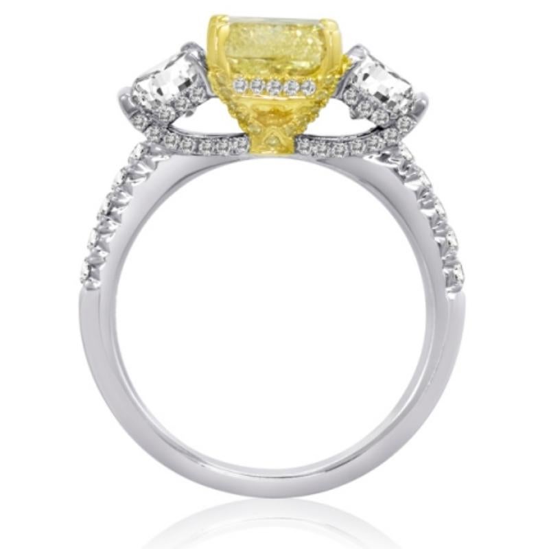 This classic three stone ring is set apart by it superb quality and vivid color. Featuring a 1.73 carat fancy yellow diamond center graded as a VS2 by GIA, two white diamond side stones totaling just over a carrat, and 60 accent stones totaling .35
