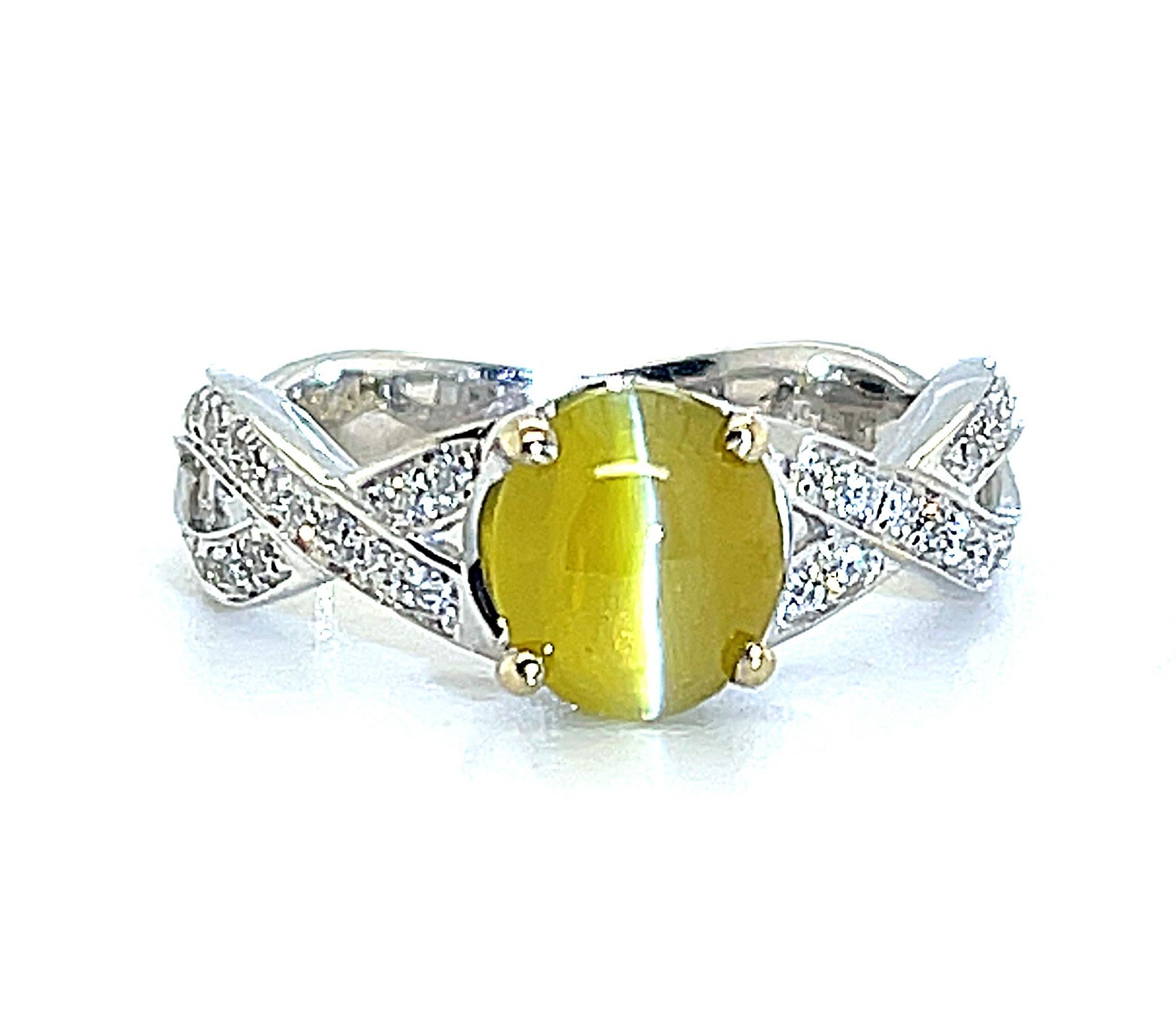 A fine, 1.73 carat cat's eye chrysoberyl cabochon is set with sparkling round diamonds in this 18 karat white gold band ring. The cat's eye is a gorgeous, golden-honey color with a clean, sharp eye and excellent transparency. The elegant, criss