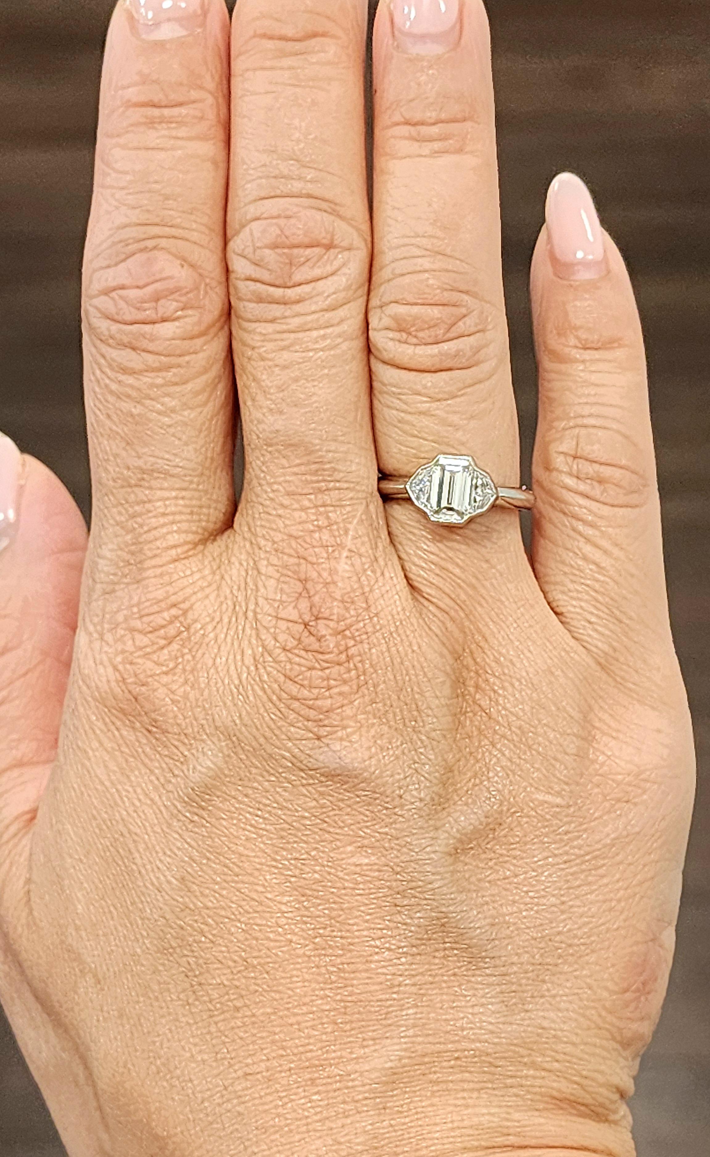 This stunning bezel set ring features a GIA certified emerald cut diamond weighing 1.23 ct. Two cadillac cut diamonds accompany the sides of the beautiful emerald weighing approximately 0.50 ct. The diamonds boasts a color of G/H with a clarity of