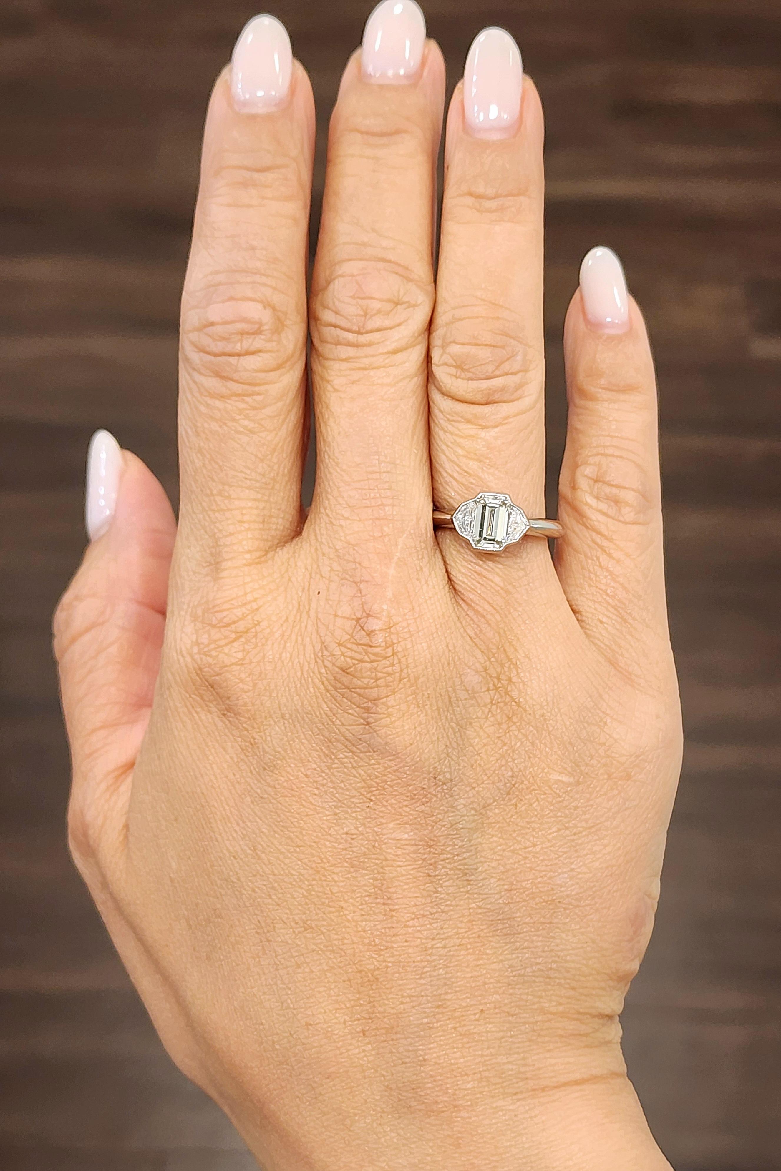 This exquisite ring showcases a GIA-certified 1.23 ct emerald-cut diamond as the centerpiece, radiating exceptional clarity and brilliance. Flanking the center stone are two cadillac-cut diamonds totaling approximately 0.50 ct, graded G/H color and