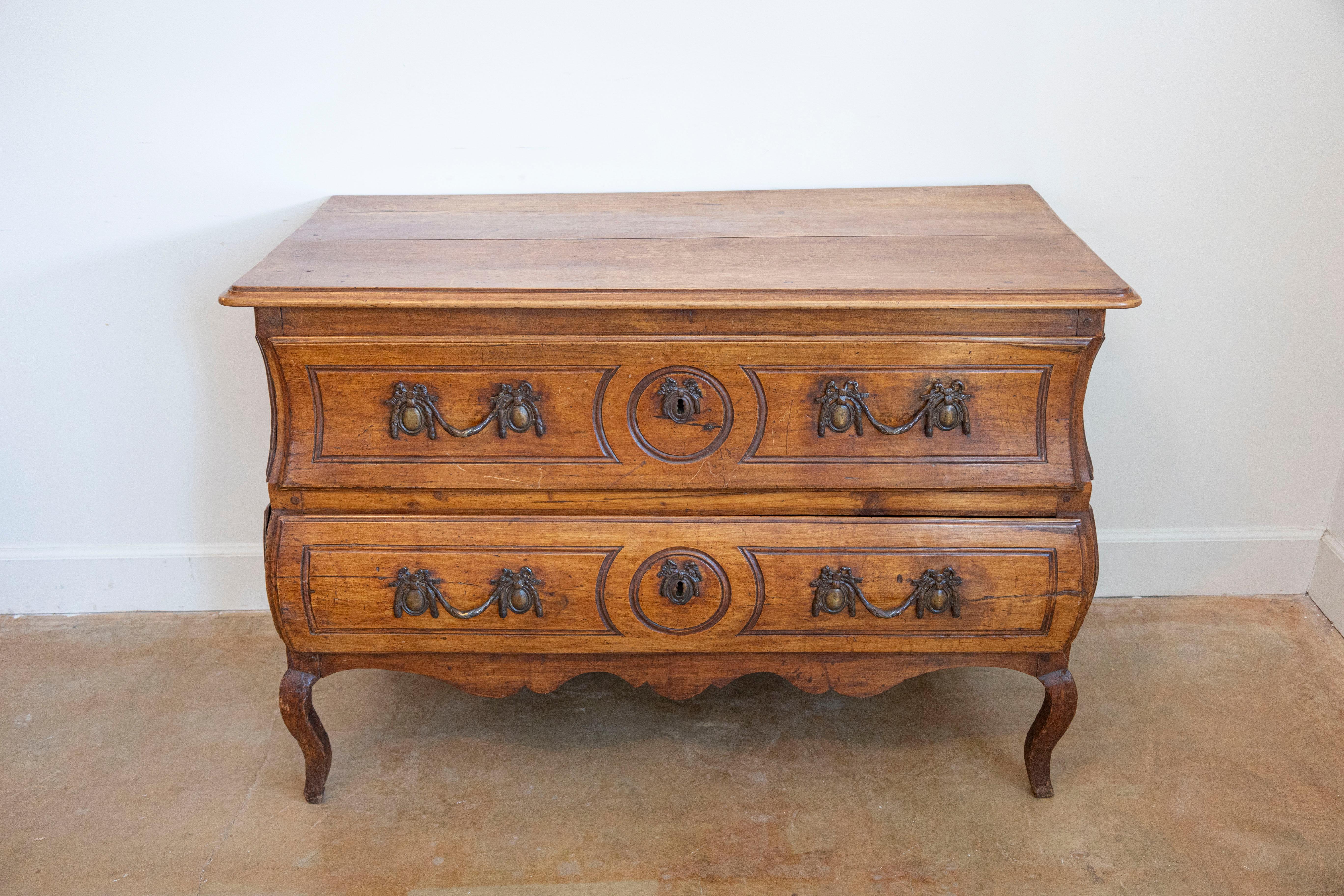 A French period Louis XV walnut two-drawer commode from the first half of the 18th century. Born in the early years of the reign of King Louis XV, This French walnut commode features a slightly raised rectangular top with rounded corners and