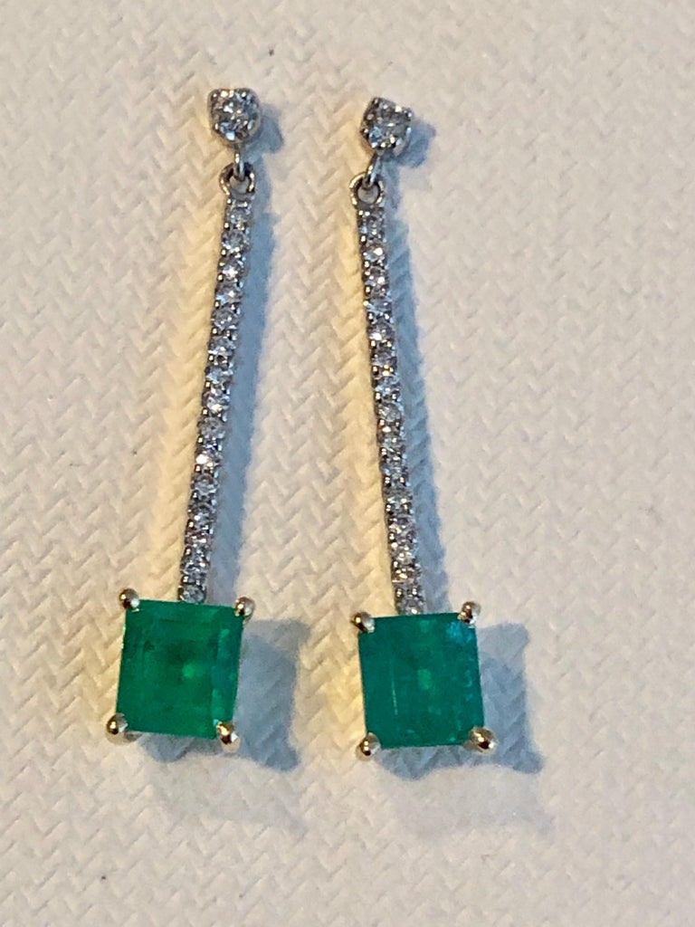 Delicate and very well handcrafted platinum and 18 karat yellow gold dangle earrings feature a top part of the earrings worked in platinum with sparkly round brilliant cut diamonds. At the bottom of the earrings dangle a beautiful deep forest green