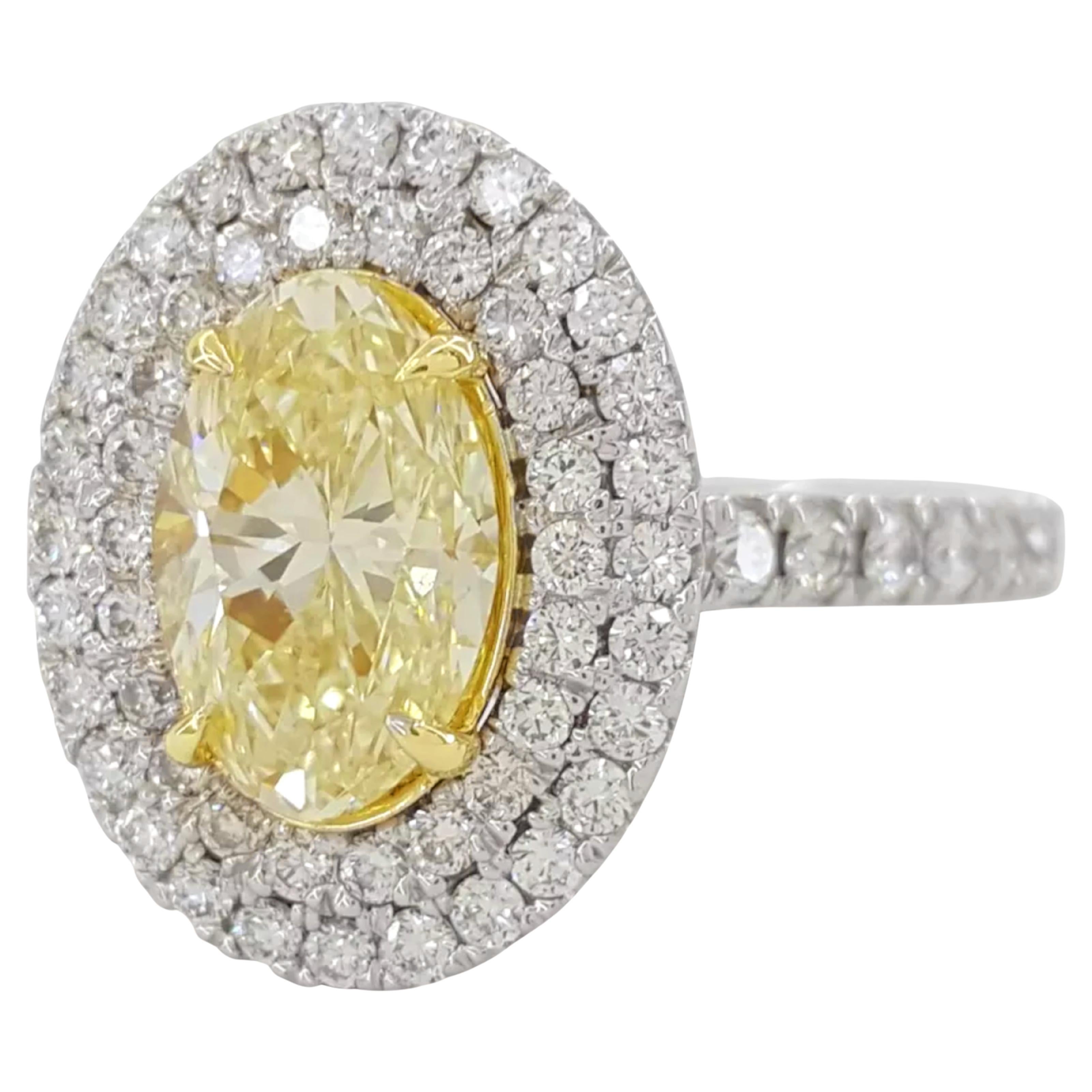 Crafted in 14K white gold, this exquisite engagement ring showcases a 1.74 carat natural oval brilliant cut diamond at its center. The diamond, Fancy Light Yellow in color and SI1 in clarity, is beautifully complemented by a double halo design.

The