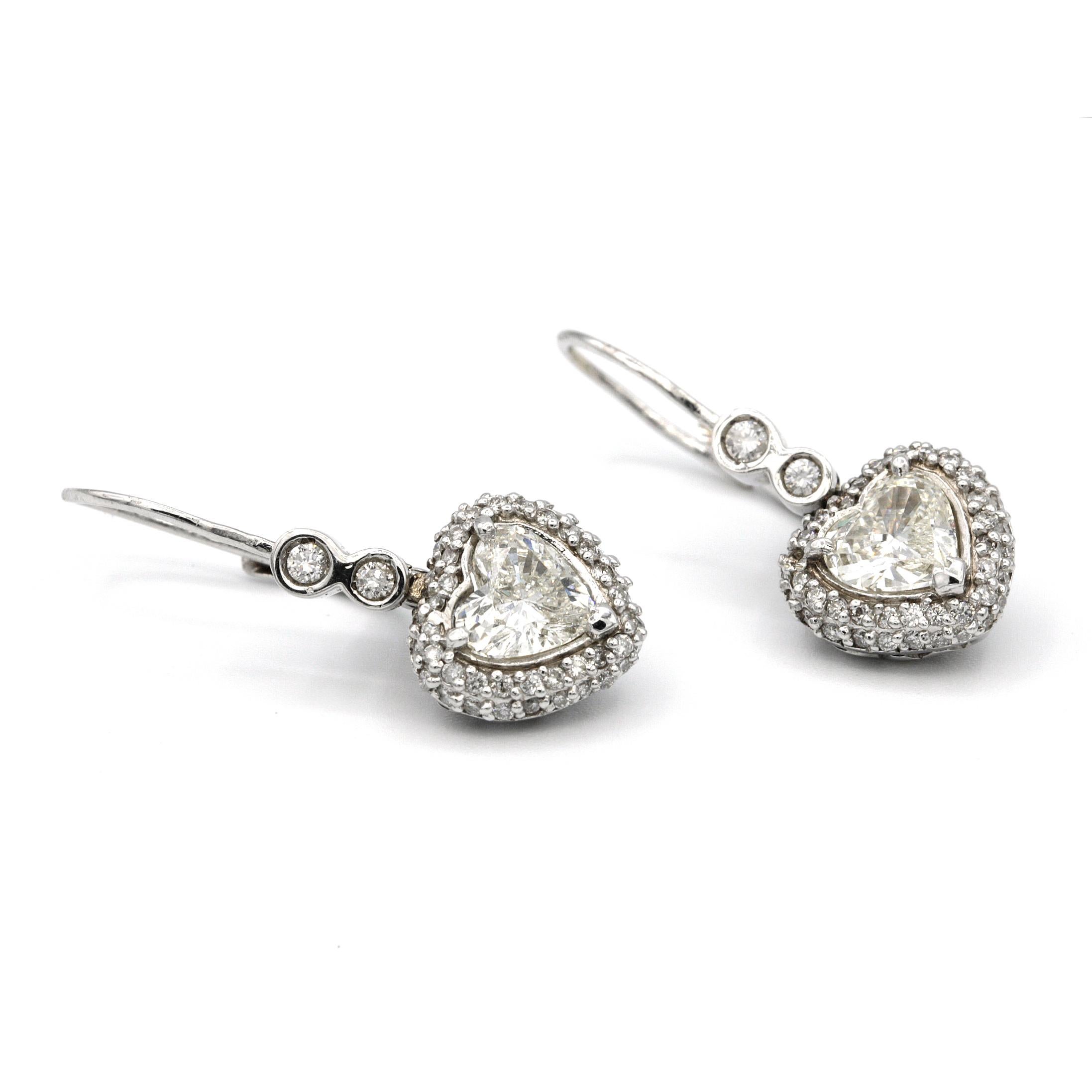 These 14 karat white gold dangling pair of Heart Shaped 1.74 Carat Earrings features two round diamonds weighing 0.05ct and 0.03ct on top. 
each heart shape diamond is surrounded by 50 white round diamonds of 0.01ct each.
3cm in Length and 1cm Width
