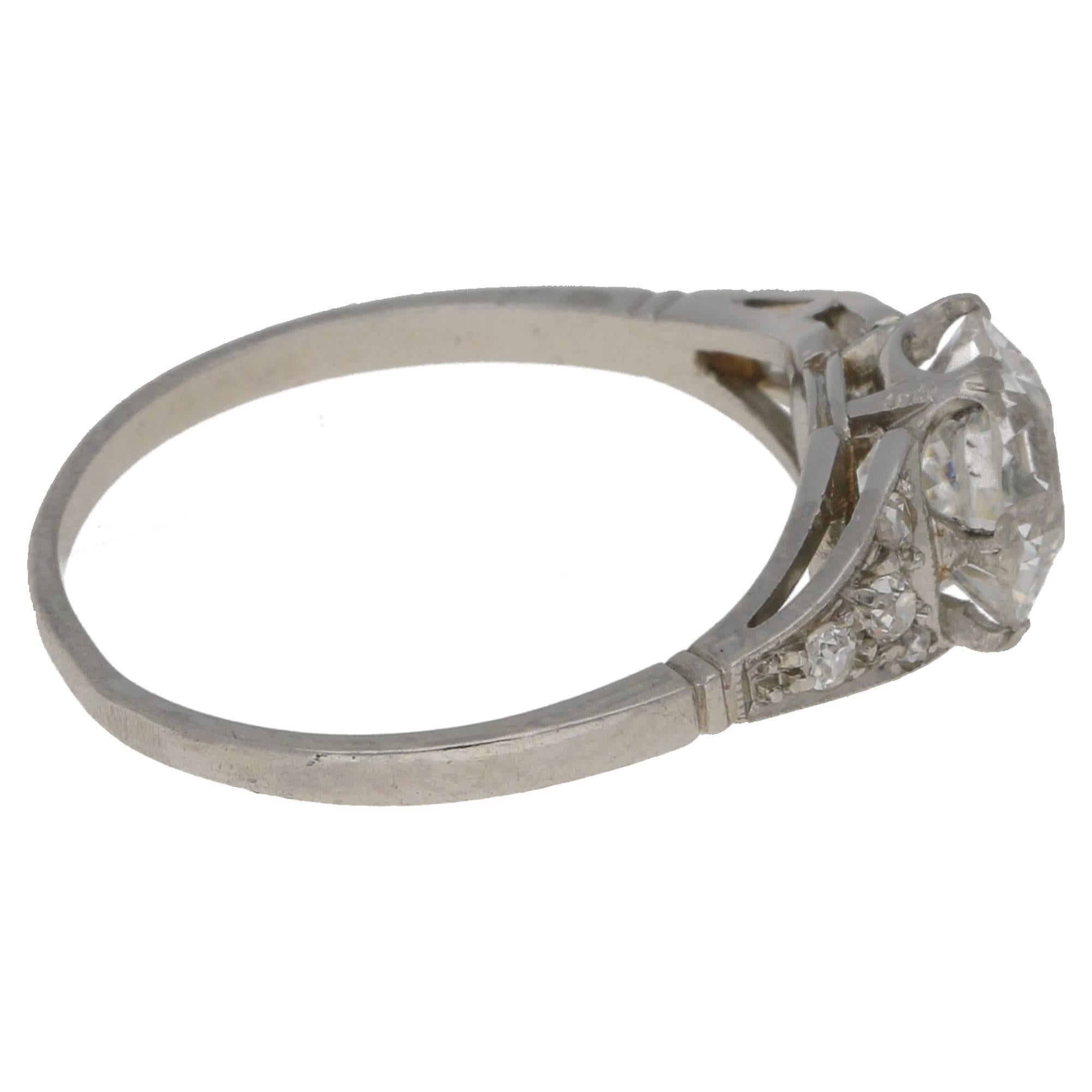 A unique and gracefully styled Art Nouveau diamond set ring. The centrally set transitional round brilliant cut diamond is set with six ridged claws, with fluted diamond set paneled shoulders. Estimated central diamond weight: 1.75cts. Assessed