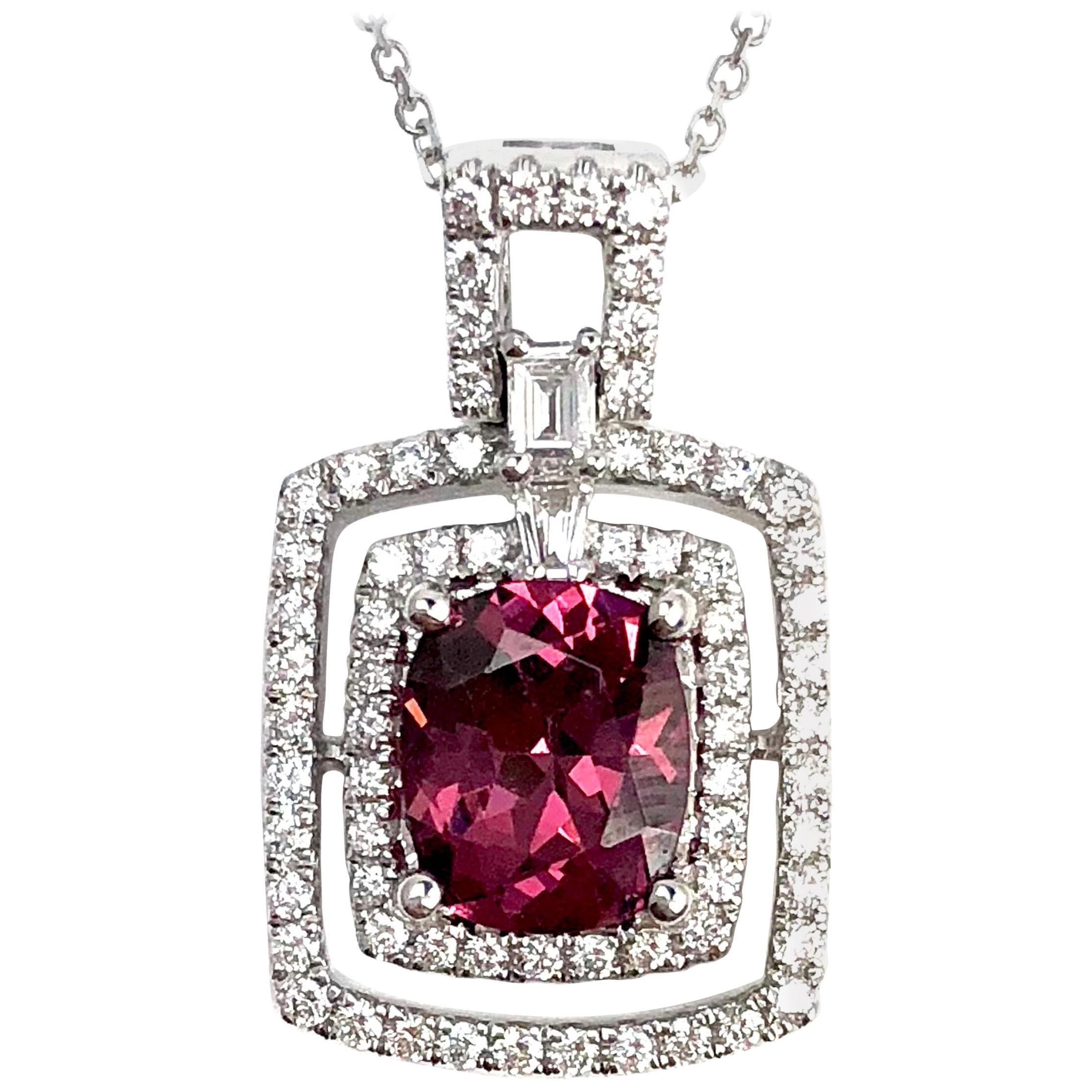 Elevate your style with a pendant that is as unique and captivating as you are. This exquisite piece showcases a 1.75 carat cushion-cut raspberry garnet, surrounded by the brilliance of round white natural diamonds, and complemented by two tapered