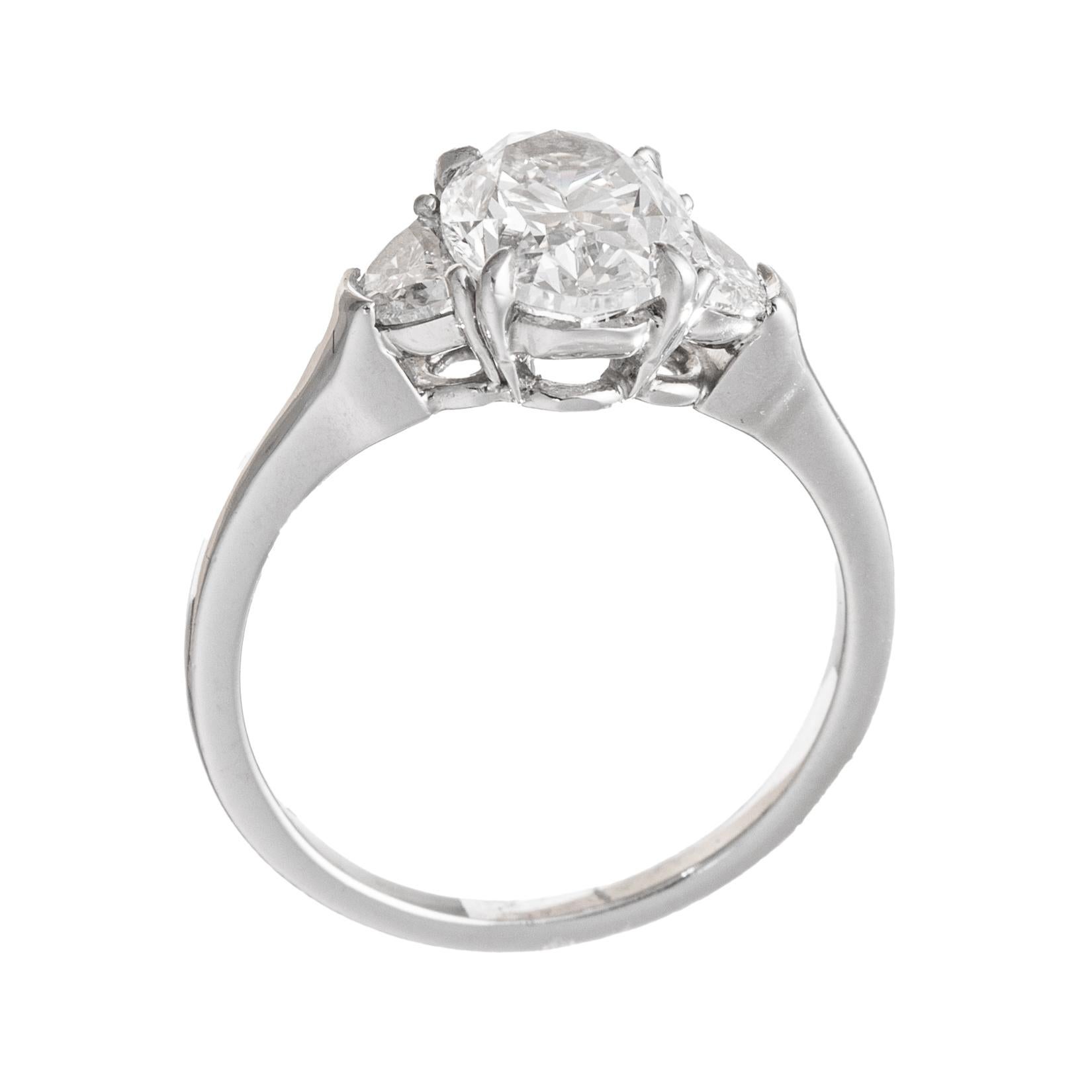 Handmade platinum and diamond engagement ring, centering a colorless oval brilliant-cut diamond weighing 1.75 carats (E-color, VS1-clarity) flanked by half moon-shaped diamond side stones.  Two half moon-shaped diamonds weighing ~0.80 total carats