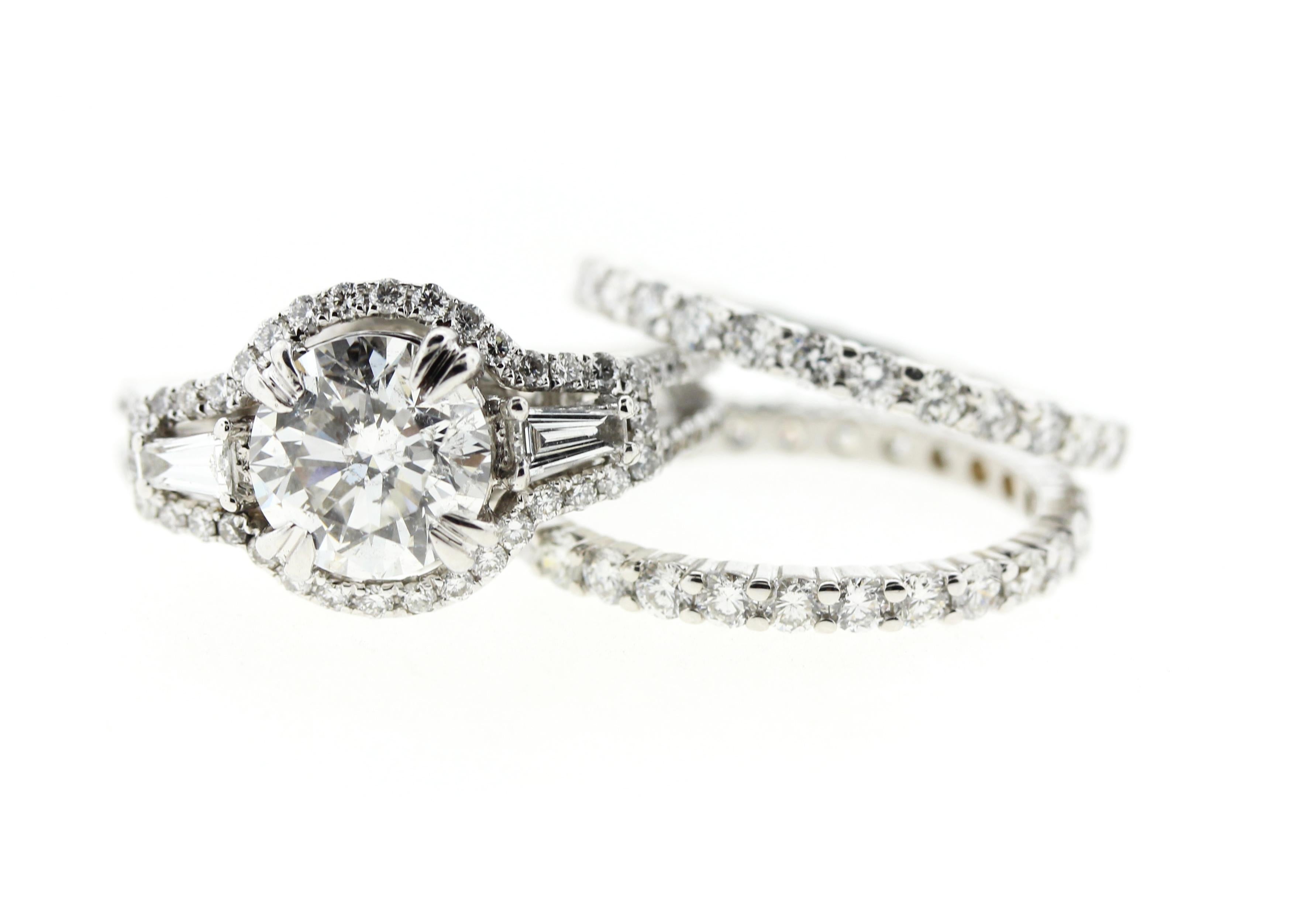 This round diamond engagement ring features a combination of multiple elements to create a truly unique look. Set in platinum, the 1.75 center round diamond is surrounded by a diamond halo. Two tapered baguettes create a timeless look while a split