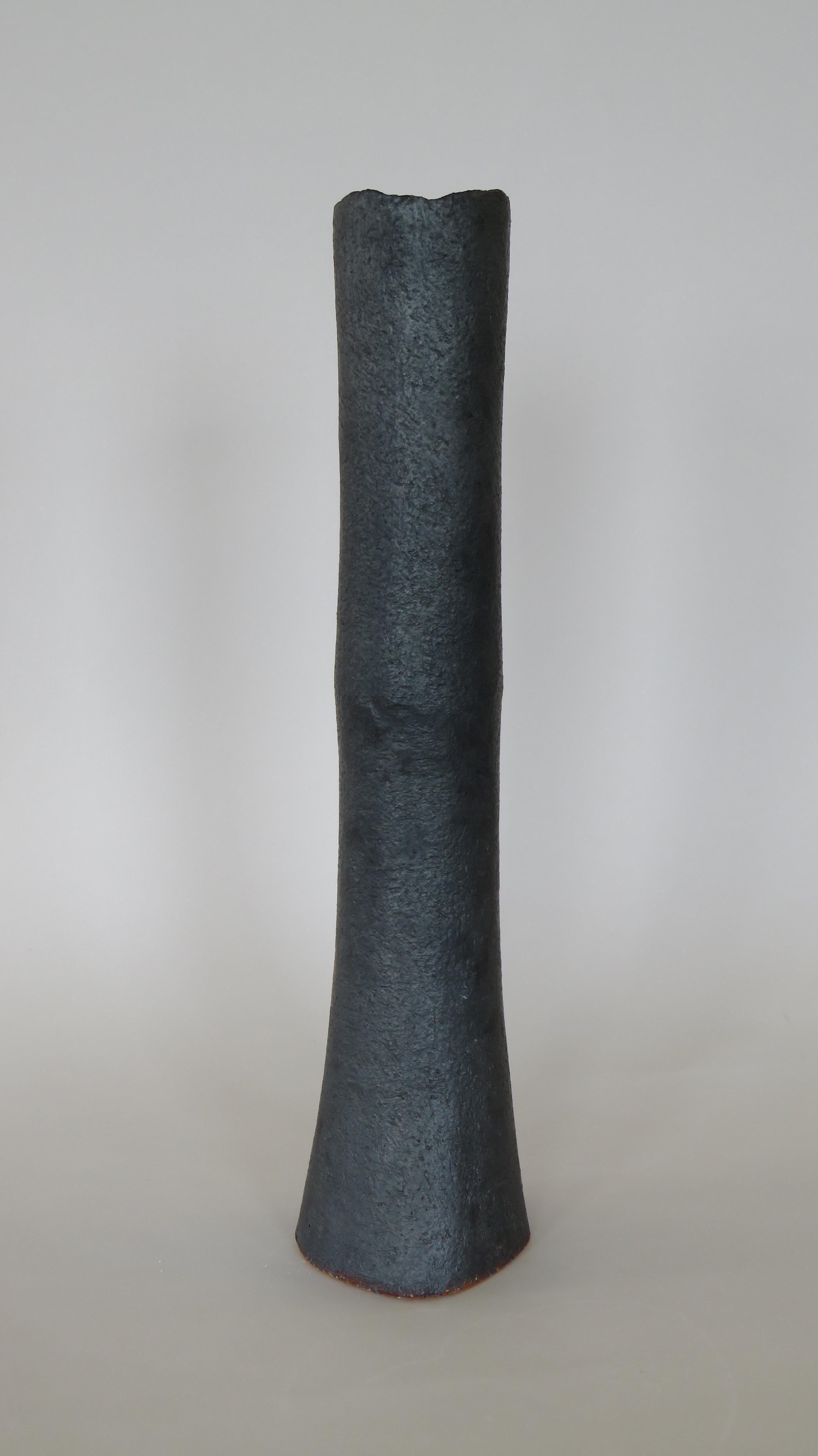 These tall vases in a metallic black glaze over stoneware are weighted on the bottom for tall floral arrangements or branches. Each surface is scraped to show the texture and tone of the clay, with varying bases or knobby edges. The top rims are
