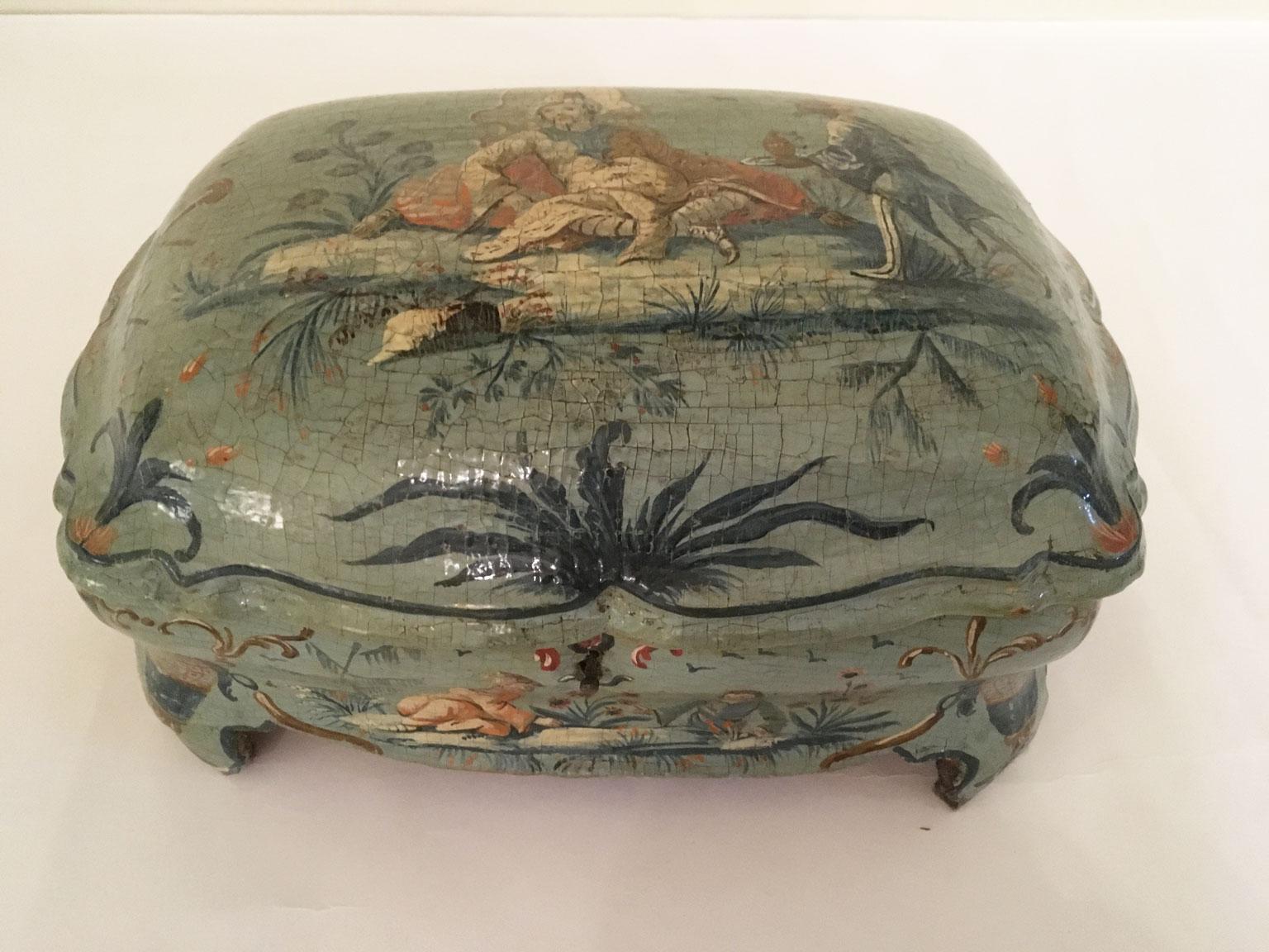Se trata de una refinada caja de madera lacada y perfilada, con figuras chinas policromadas y fina decoración floral sobre fondo verde y azul claro. 
La forma curvada de la  en la casilla  por delante, por los lados  y de los pies,  la rica talla,