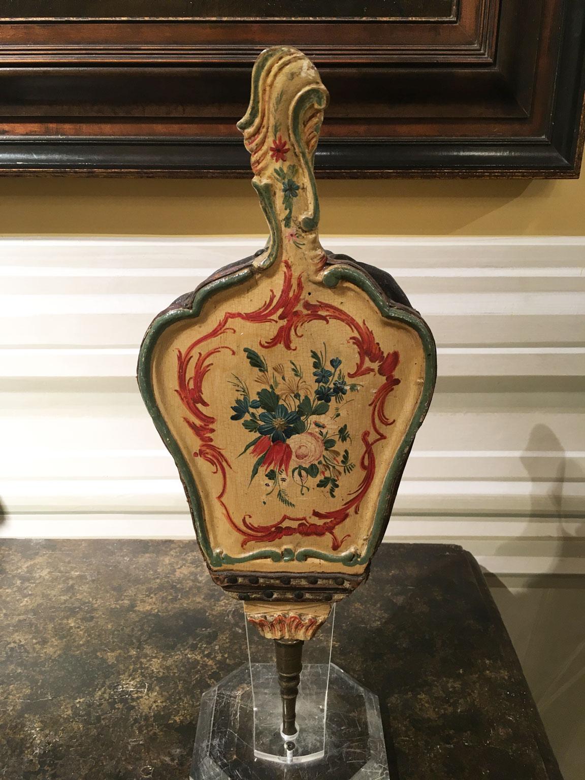 Se trata de un raro fuelle de chimenea de madera tallada y lacada con decoraciones policromas de flores sobre fondo amarillo. Tiene detalles originales de cuero y el pitorro de bronce.  Esta elegante pieza procede de mediados del siglo XVIII, de