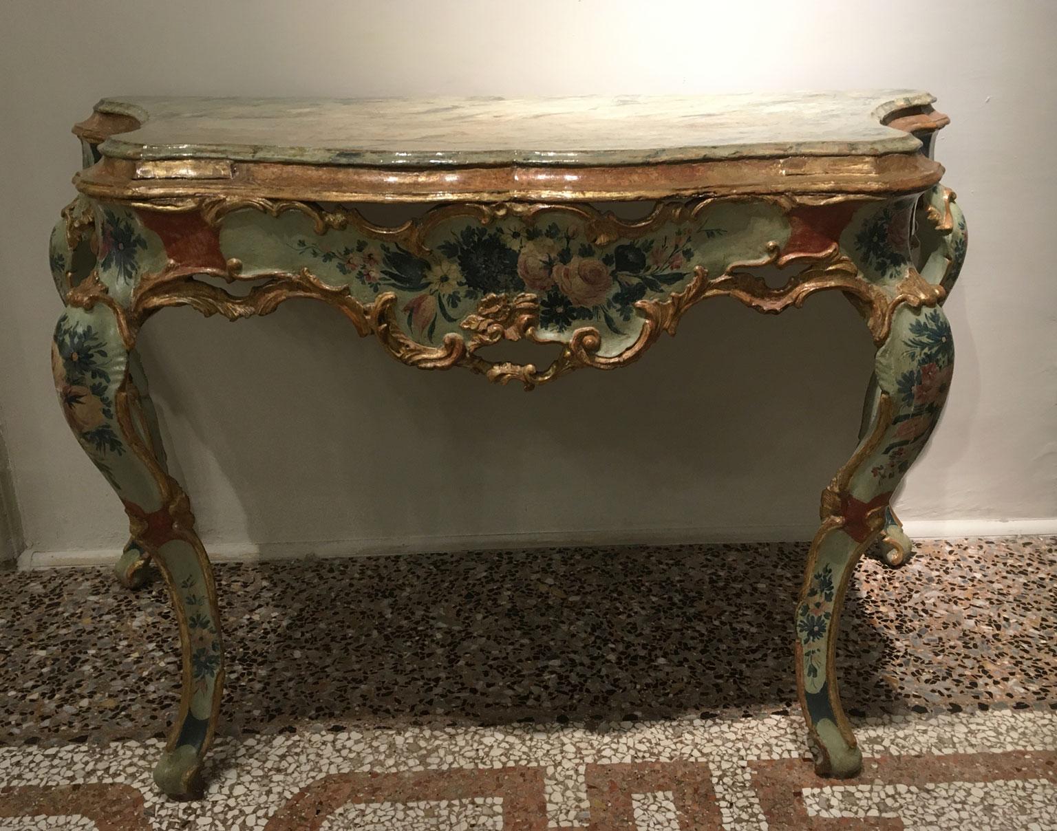 Il s'agit d'une extraordinaire console vénitienne en bois sculpté, perforé, laqué et doré, avec des fleurs polychromes sur fond bleu clair et vert. Certaines parties sont en bois doré. Le plateau est laqué pour imiter le marbre. 
La forme incurvée