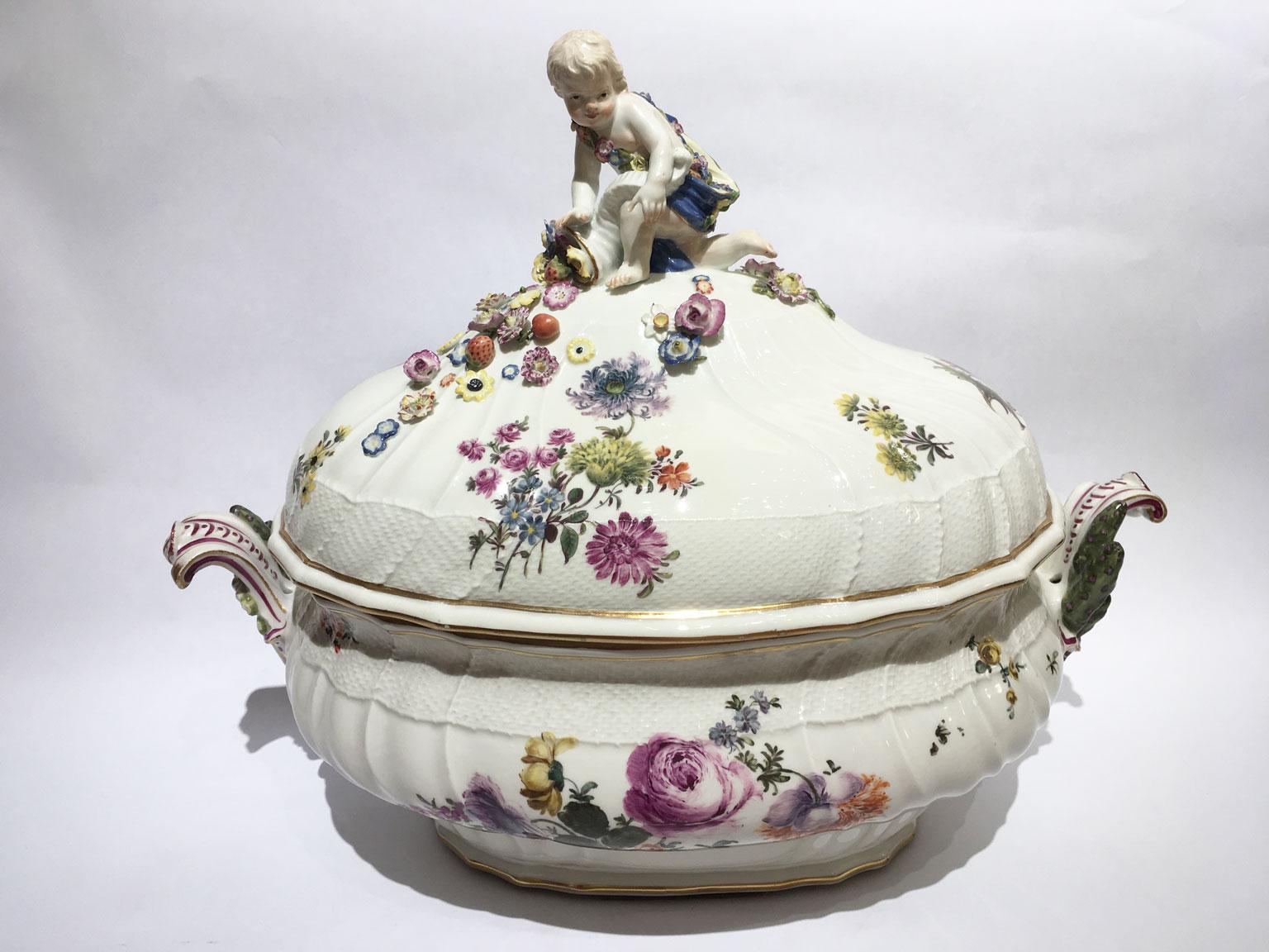 Si tratta di una spettacolare zuppiera con coperchio realizzata da Meissen nel 1755 circa. La porcellana bianca è decorata con rami di fiori multicolore e foglie di bouquet. In cima al coperchio c'è un putto con una cornucopia piena di frutta,