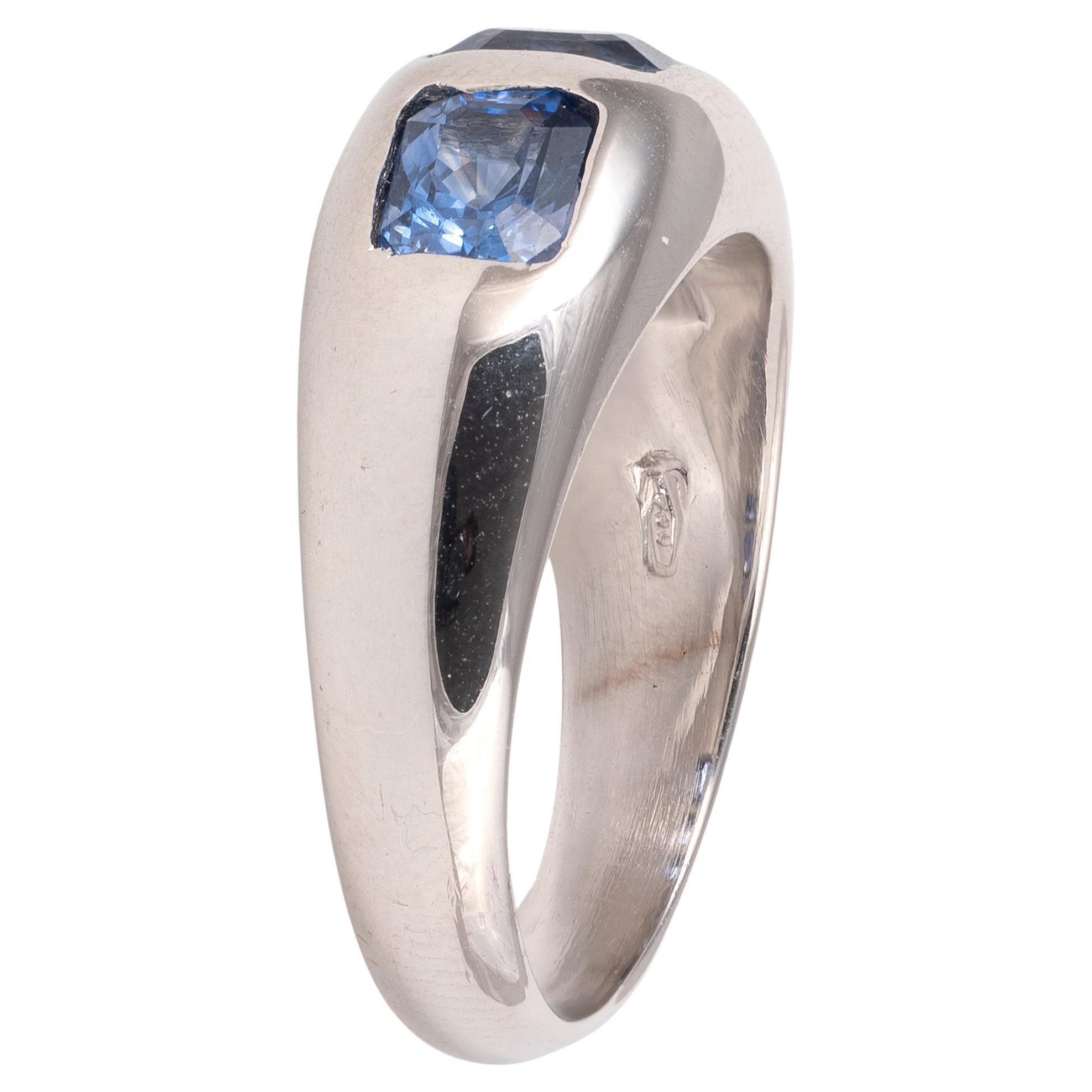 A striking sapphire and white gold three stone gypsy ring, centred with a Ceylon sapphire rectangular cut weighing 0.72ct set flush into the gold between two further Ceylon sapphire weighing 1.03cts combined, all set in an 18ct white gold flat