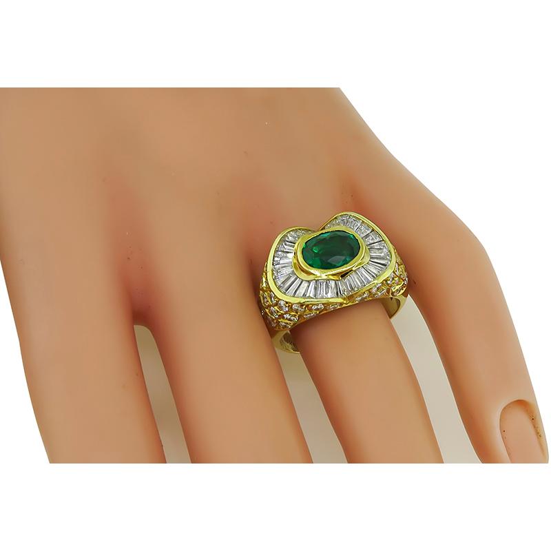 This is a gorgeous 18k yellow gold ring. The ring is centered with a lovely oval cut emerald that weighs approximately 1.75ct. The center stone is accentuated by sparkling round and baguette cut diamonds that weigh approximately 1.75ct. The color of