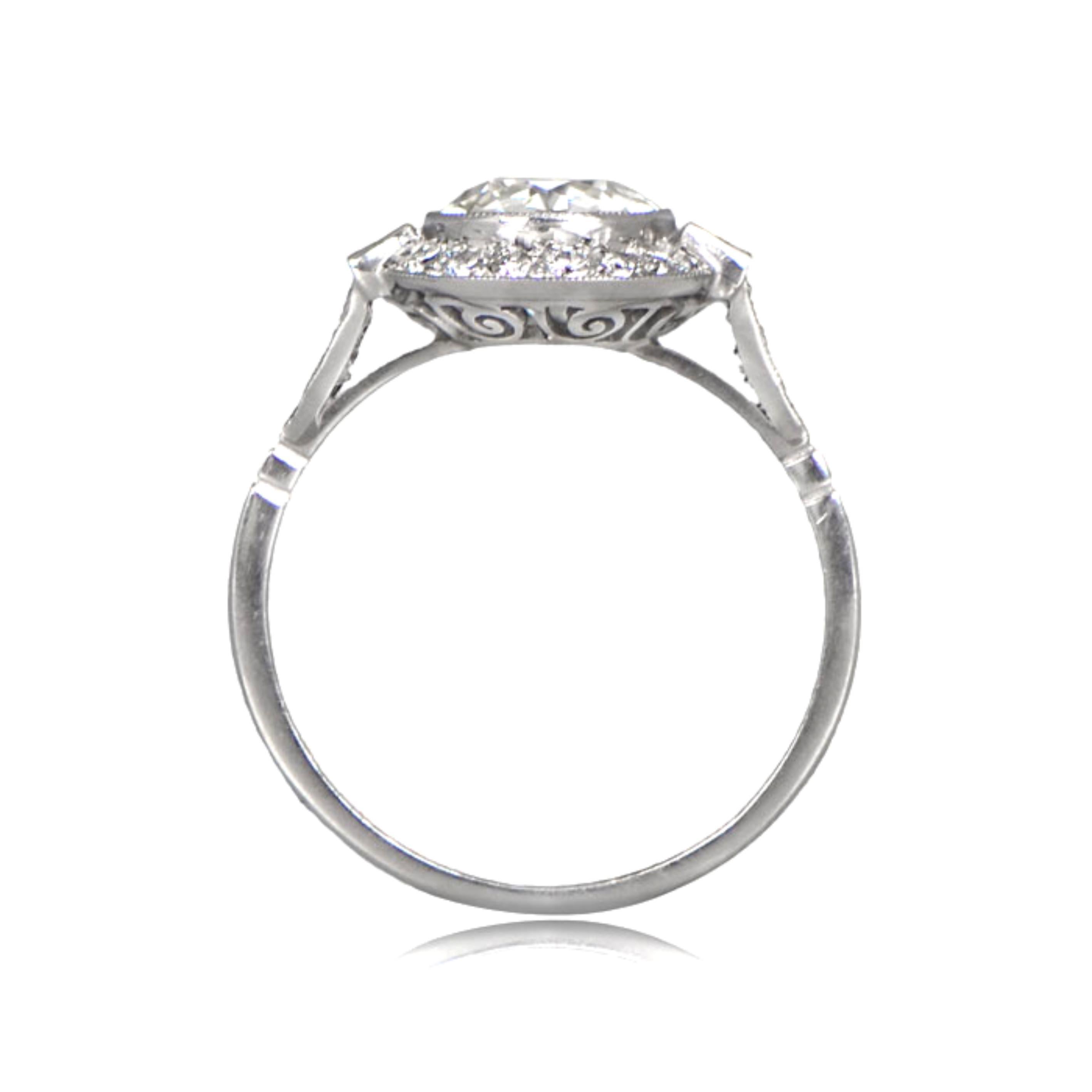 The handcrafted platinum mounting of this stunning ring features a center antique old European cut diamond surrounded by a diamond halo and flanked by baguette-cut diamonds. The shoulders are also adorned with diamonds, while the lower gallery