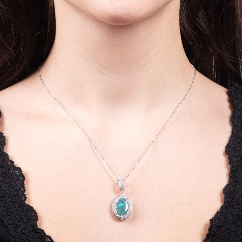 This stunning 1.75ct, oval cut, natural black opal from Lightning Ridge, Australia is surrounded  by a halo of 0.71ct total weight round diamonds, set in an 18kt white gold necklace. This sophisticated pendant adds color and intrigue to your jewelry