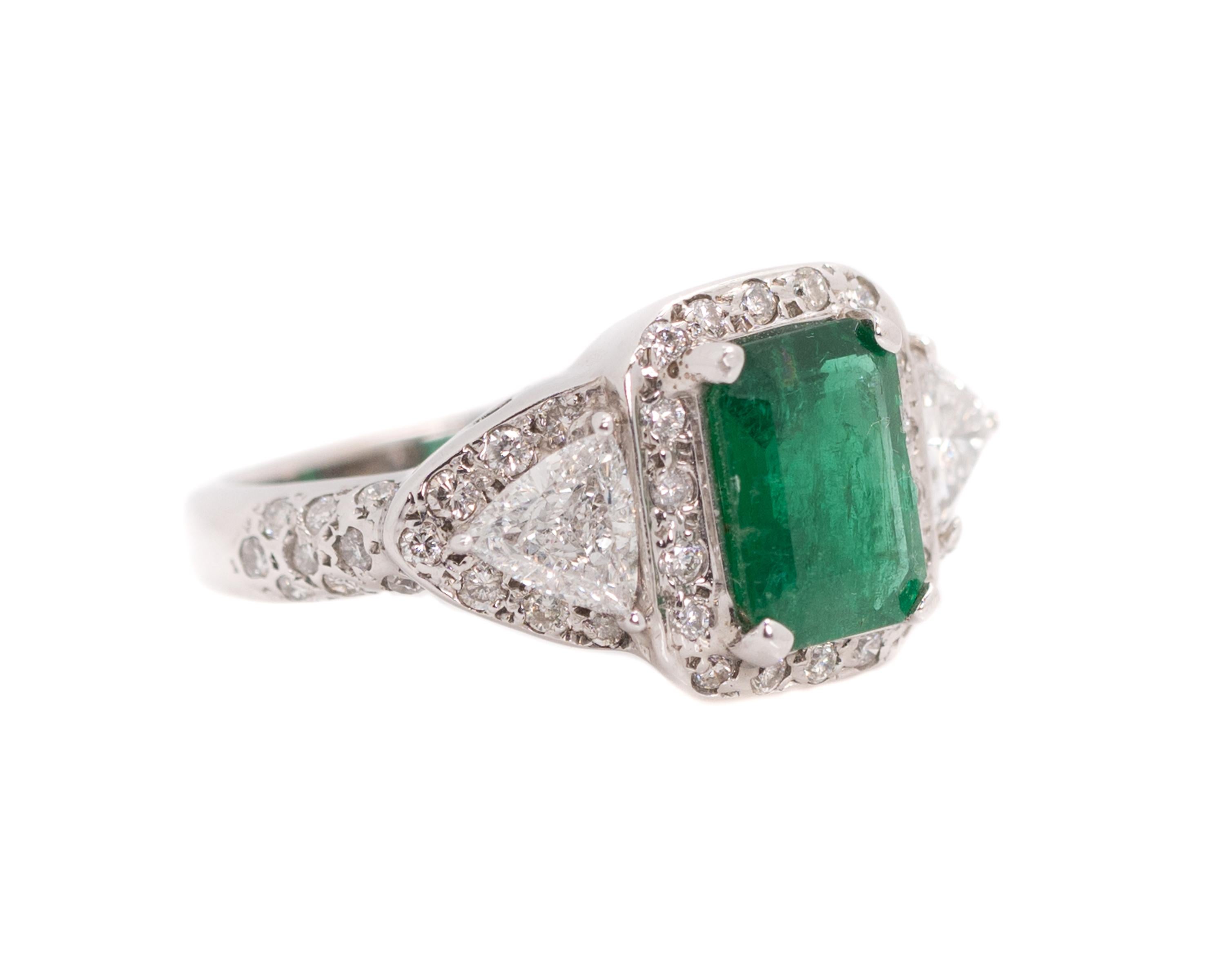 1980s Emerald Ring - 18 Karat White Gold, Emerald, Diamonds

Features:
1.76 carat Emerald cut Colombian Emerald with Round Brilliant Diamond Halo
4-prong set center stone
1.4 carats total weight Trillion and Round Brilliant Diamonds
18 Karat White