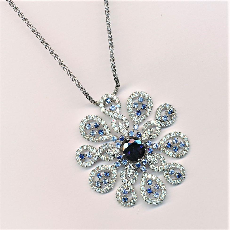 Round Flower shape pendant with a central  1.76 carat Iolite, numerous  sapphires 1.44 carat and  2.93 carat
round brilliant cut Diamonds.
The necklace is 18 k white gold.
Chain is 42 cm long. 
The high quality of this jewel is the expression of the