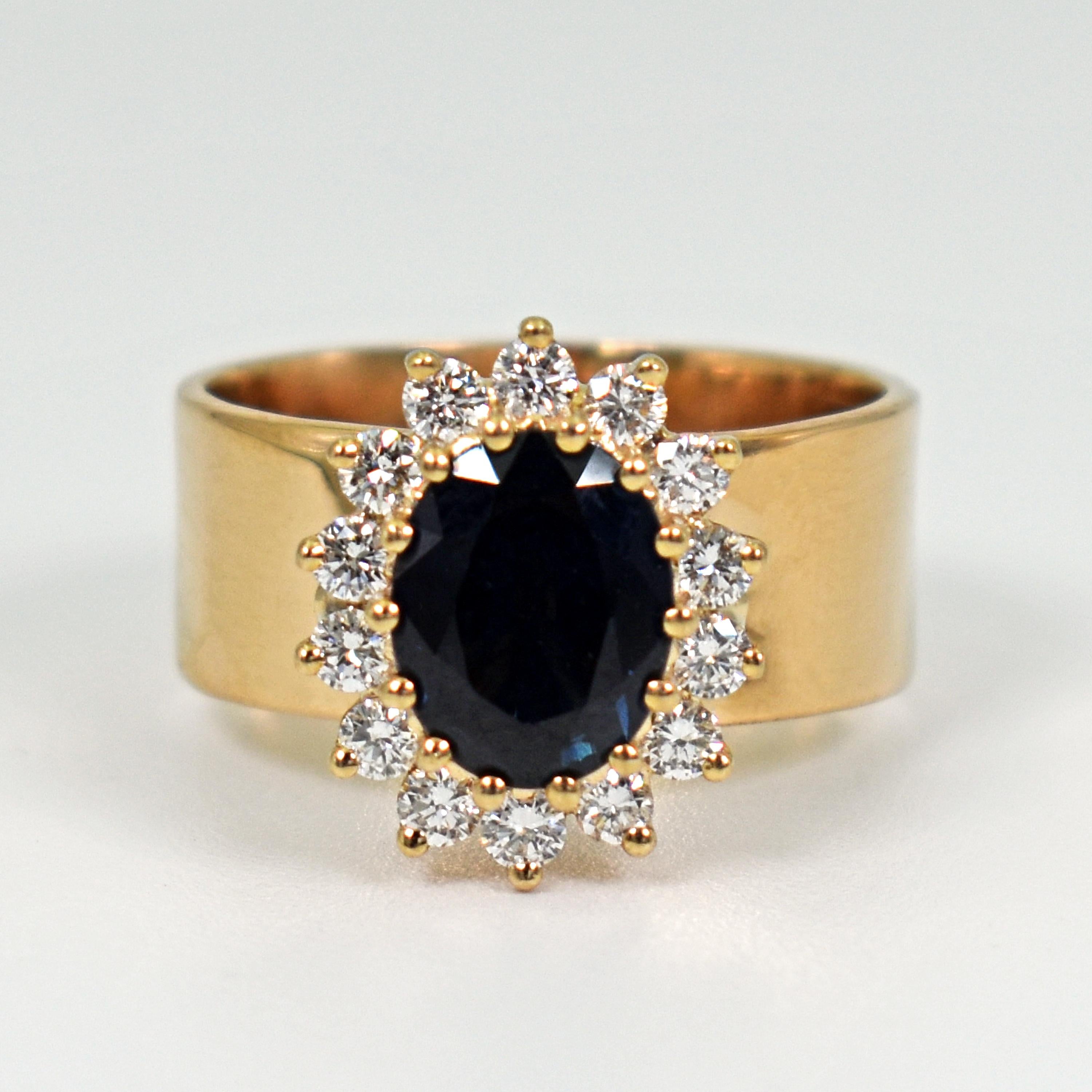 1.76 carat oval Blue Sapphire and white Diamond halo (0.42 cttw, G-H, SI1) in 14k yellow gold prong setting on an 18k yellow gold ring band. Ring is currently size US 6.5 and can be resized. Ring band is 7mm wide. Timeless meets contemporary in this