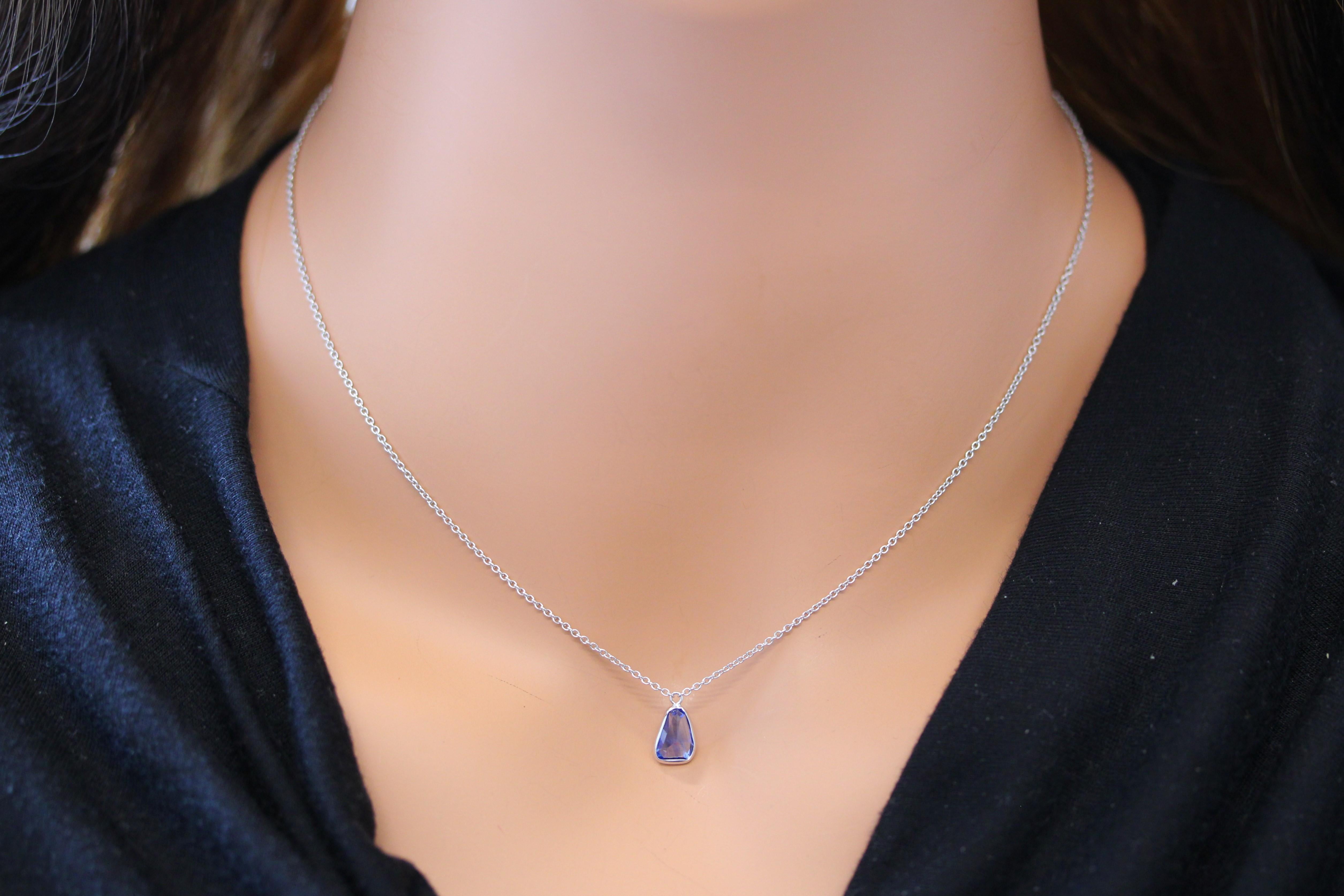 The necklace features a 1.76-carat triangle-cut blue sapphire set in a 14 karat white gold pendant or setting. The unique triangle cut and the blue sapphire's color against the white gold setting are likely to create a distinctive and stylish piece