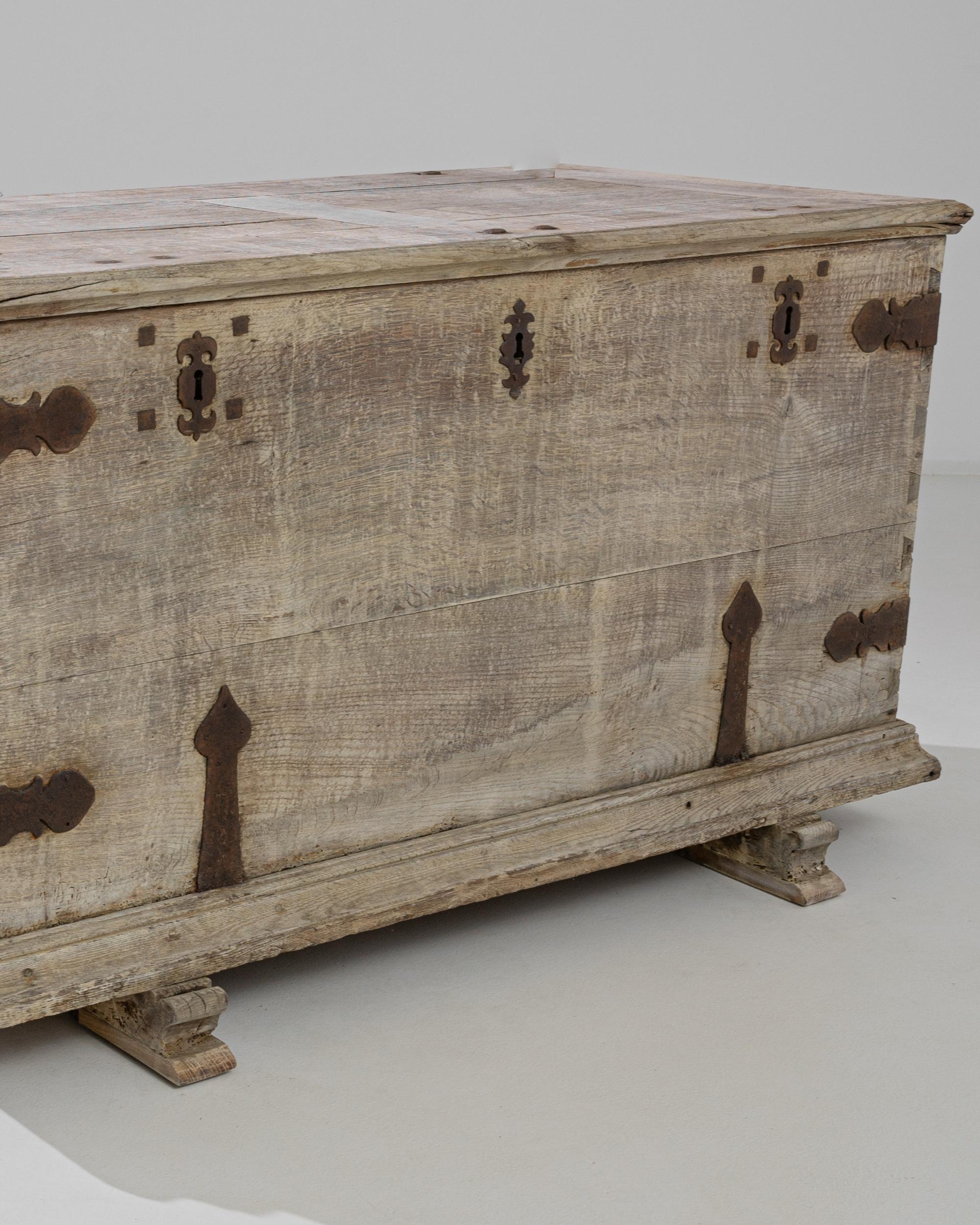 A bleached oak trunk from France, produced circa 1760. A gorgeous antique trunk in pale oak: a big box constructed with dovetail joints, held together with iron braces that add a flourish as they wrap around the corners. This piece features an