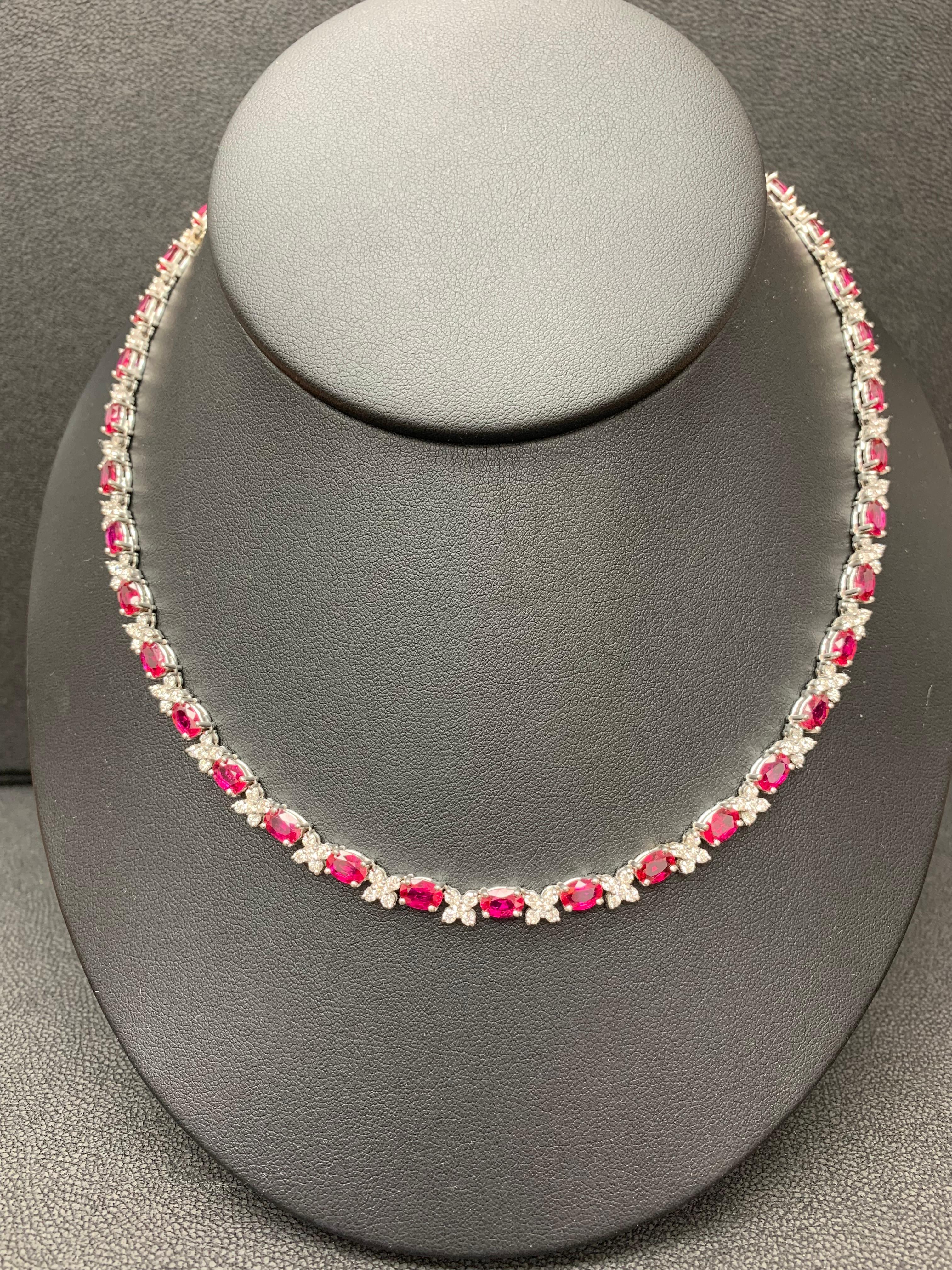 An incredibly color-rich tennis necklace showcasing 17.68 carats total of 39 oval cut red rubies, each elegantly spaced by 149 round brilliant diamonds in flower shape setting weighing 4.90 carats total. Made in 14k white gold. Approximately 16
