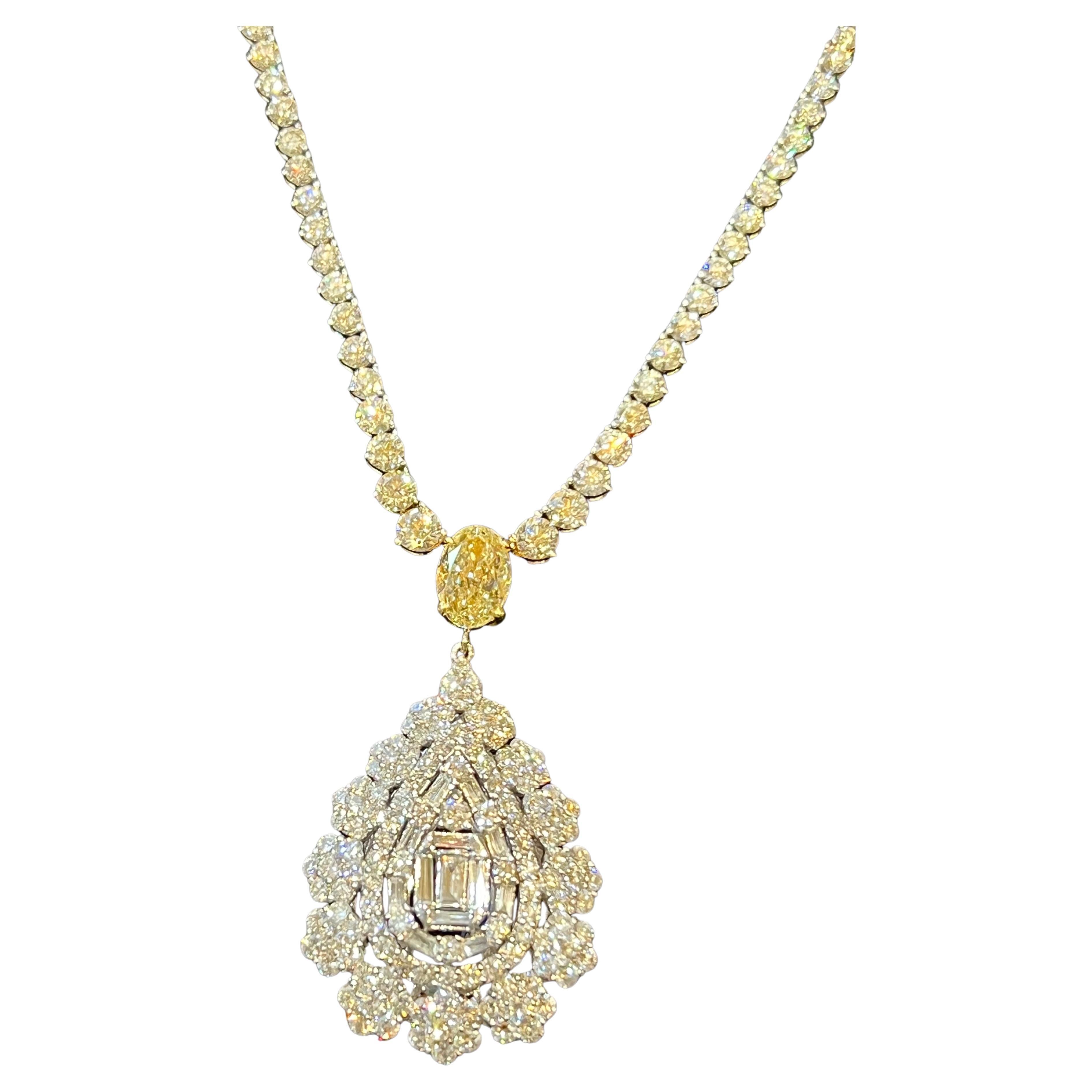 Very elegant, 18 karat white gold graduated diamond tennis necklace with diamonds that go all the way around the entire neck, features a 2.29 carat oval shaped fancy yellow diamond connected to a slightly domed pear shape cluster diamond drop. The
