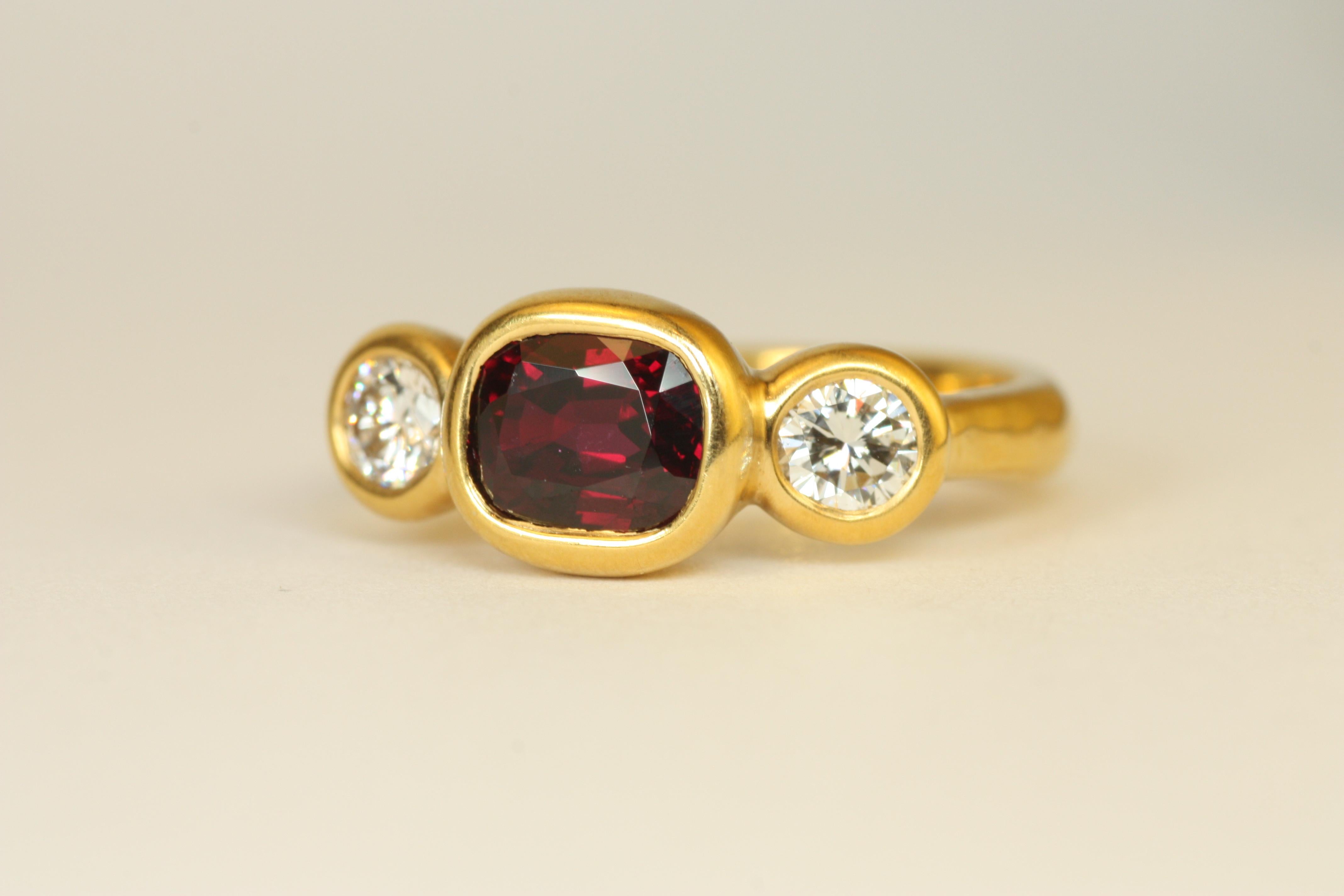 Présentant un rubis rouge profond dans une monture ovale est-ouest, cette bague capture un sentiment de luxe et de charme vintage. Sertie dans de l'or jaune 22k martelé, la couleur intense du rubis est magnifiquement complétée par deux diamants