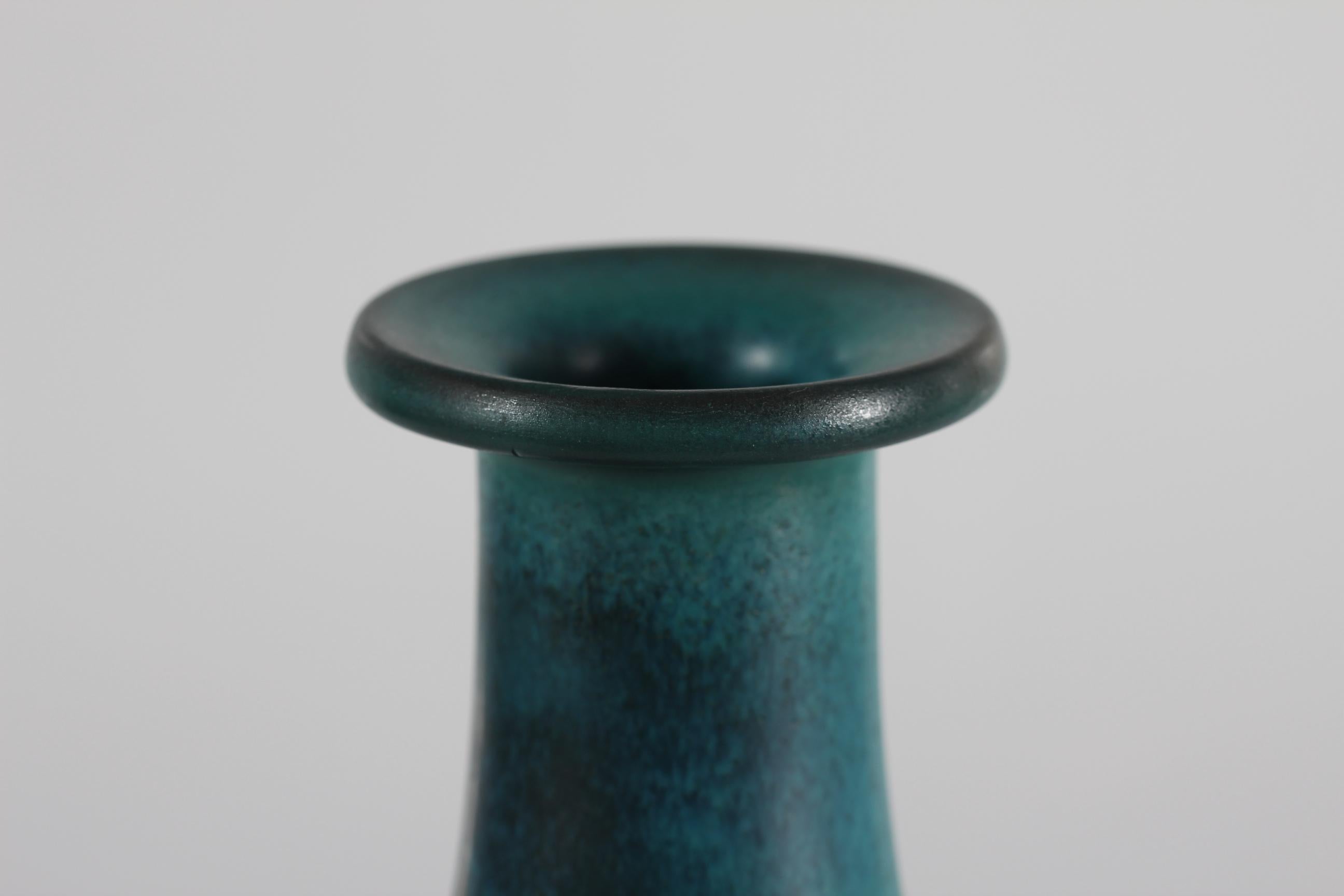 This very tall and slender vase was designed by Gunnar Nylund for Nymølle and produced in Denmark, circa 1960´s. It has a vivid blue green glaze over a radiating pattern. Measure: 17.7” Tall.

The vase is a first edition and in very good vintage