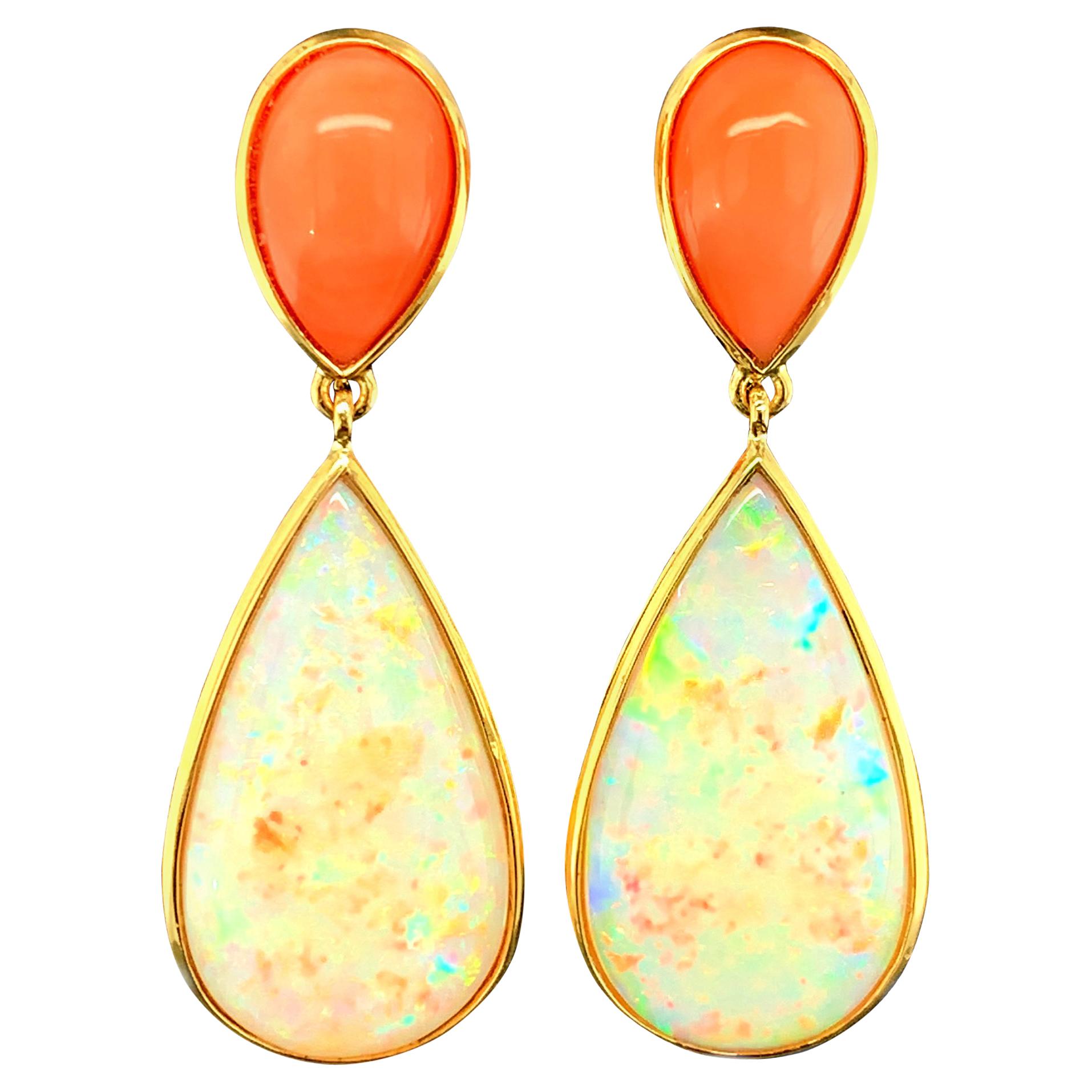 These eye-catching drop earrings feature a lovely combination of large colorful opals paired with peach-colored coral! The opals have been cut as pear-shaped cabochons whose elegant shape is highlighted by setting them in sleek 18k yellow gold