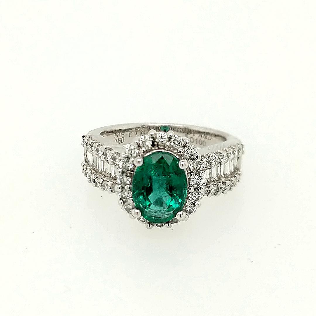 This emerald and diamond ring is crafted in 18k white gold featuring (1) oval emerald weighing 1.78 carat. The emerald is surrounded by 39 round diamonds weighing .64cttw and (12) baguettes weighing .36cttw. 
