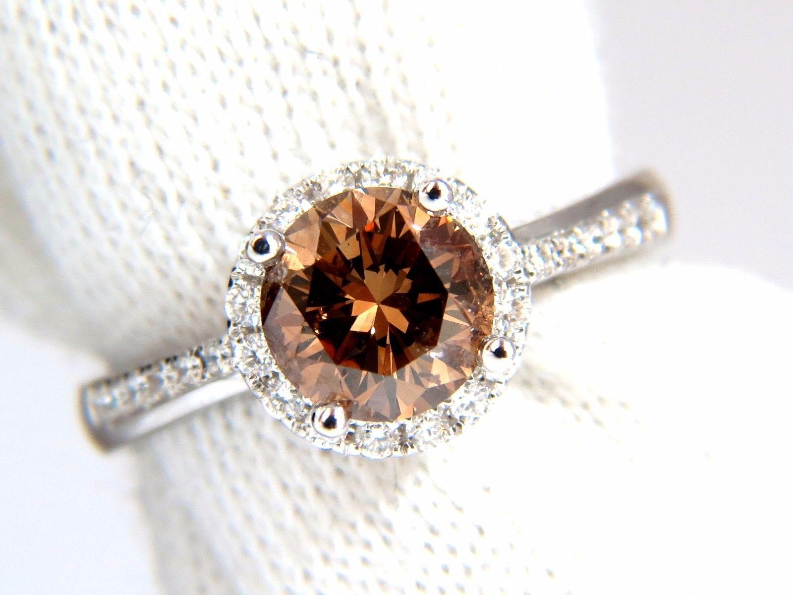 Raised Solitaire Round.

1.28ct. Natural round diamond ring

Fancy vivid orange brown color

 Si-1 clarity 

Very good Cut / Full cut Brilliant

Side round white diamonds:

.50ct G-color & Vs-2 clarity.

18kt white  gold

Ring size: