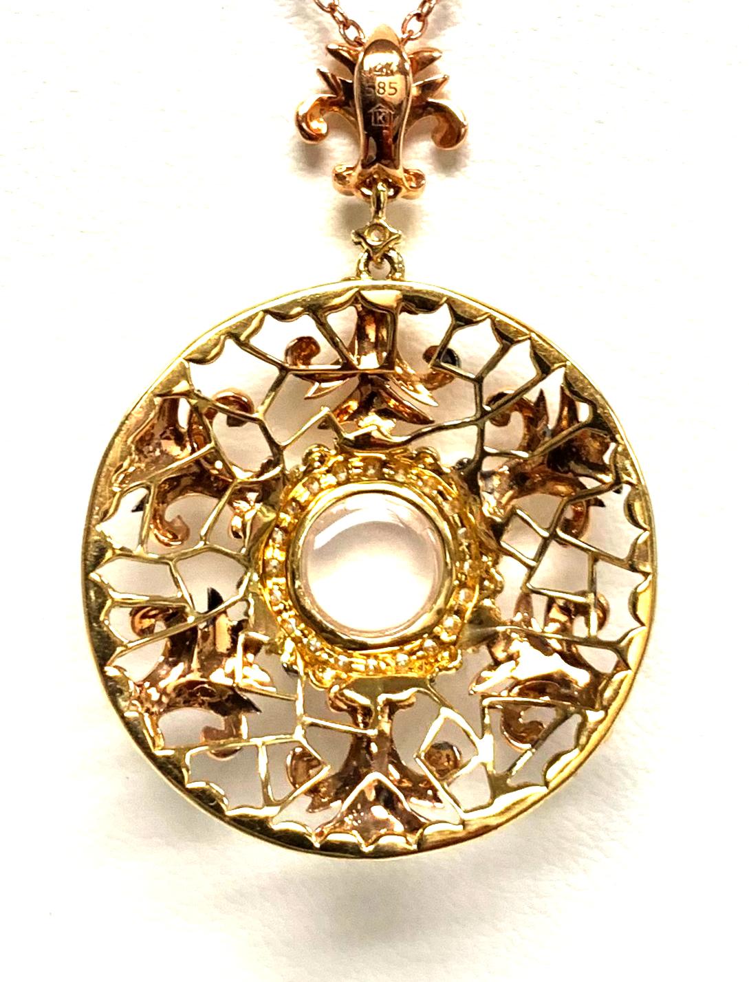 This intricately designed pendant features a 1.78 carat round moonstone cabochon at the center of a diamond studded halo and framed by beautiful 14k rose gold accents. The moonstone exhibits mesmerizing adularescence, or 