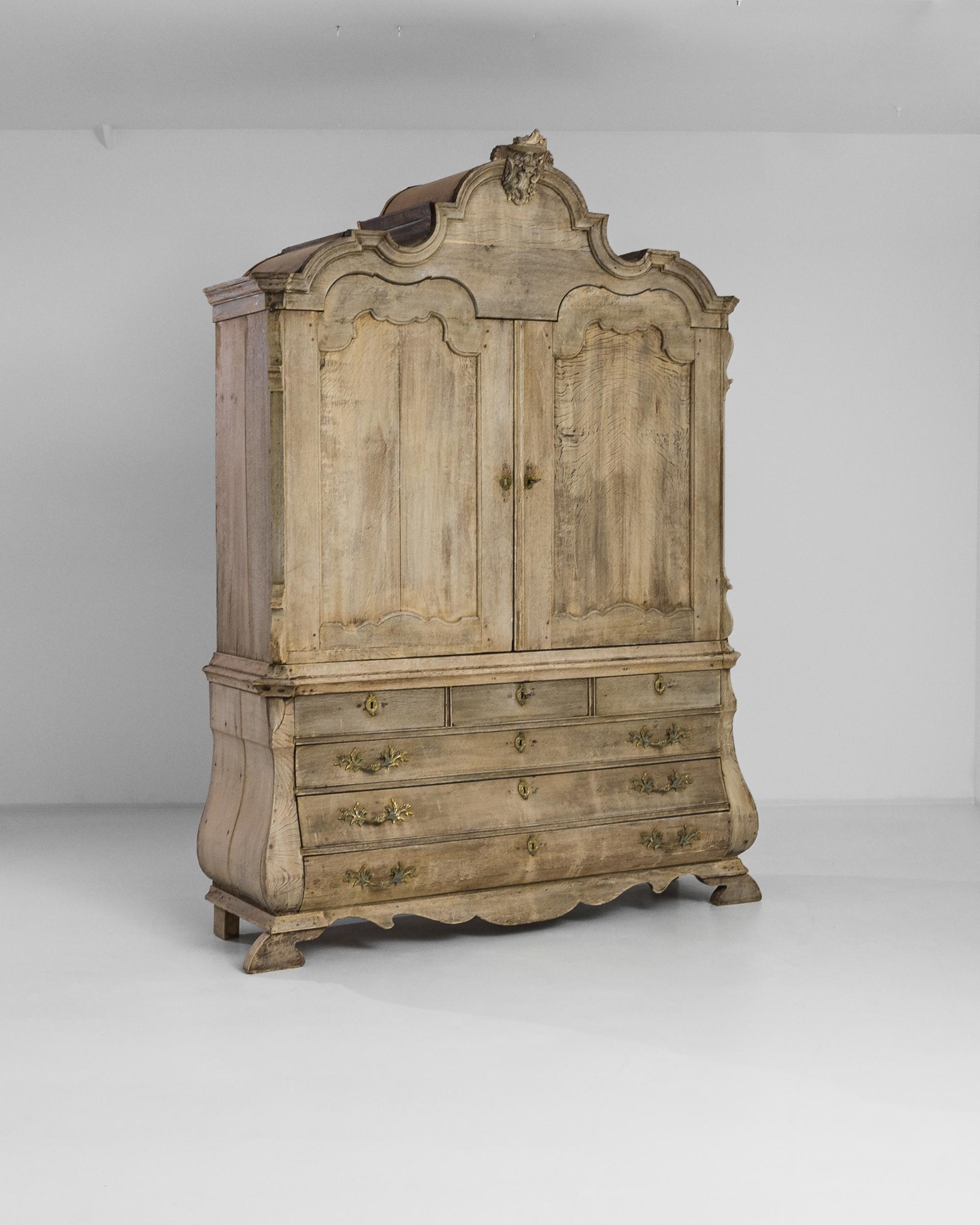 This bleached oak cabinet was produced in the Netherlands at the end of the 18th Century. A tall wooden case rests on a slightly bombé chest featuring an arrangement of six drawers, completed by three hidden ones inside the upper chest. The two