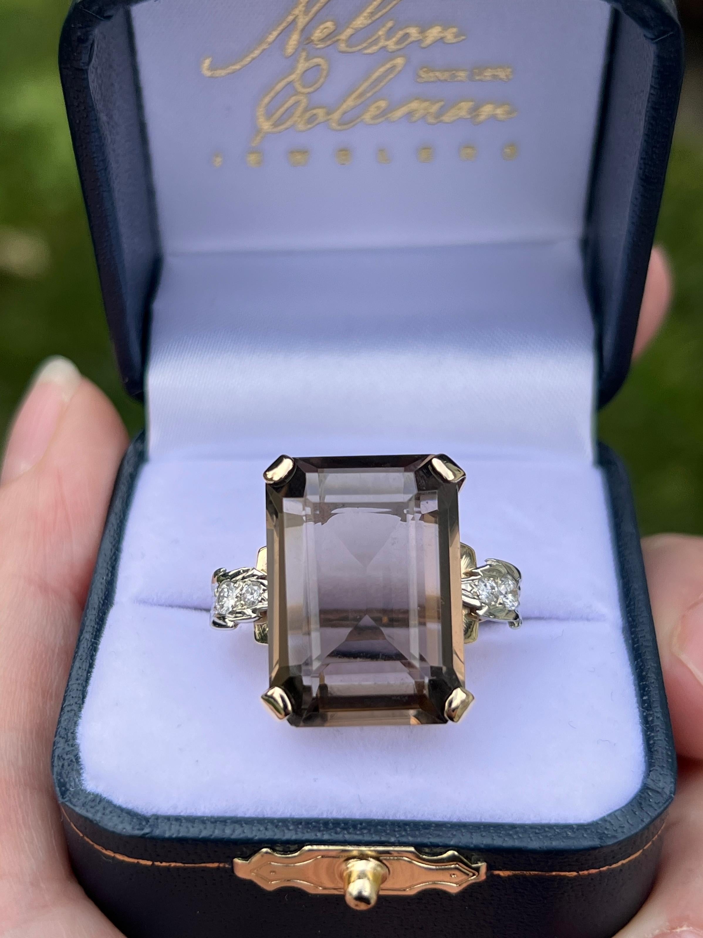 Un audace e affascinante anello da cocktail degli anni '40 realizzato in oro giallo e bianco a 14 carati. Al centro si trova un quarzo fumé con taglio smeraldo dalle dimensioni di 21,6 x 15,6 x 8 mm e dal peso di circa 17,86 carati. Conosciuto per