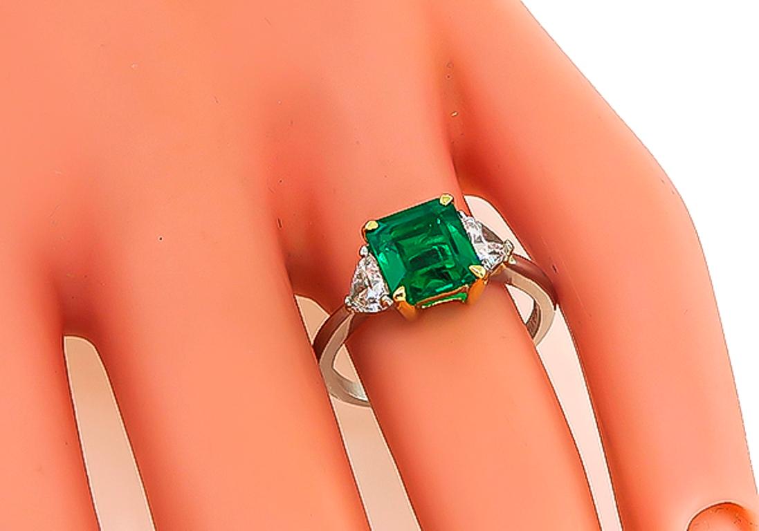 This platinum engagement ring is centered with a lovely Colombian emerald that weighs 1.79ct. The emerald is accentuated by sparkling trilliant cut diamonds that weigh approximately 0.50ct. graded H color with VS clarity. The top of the ring