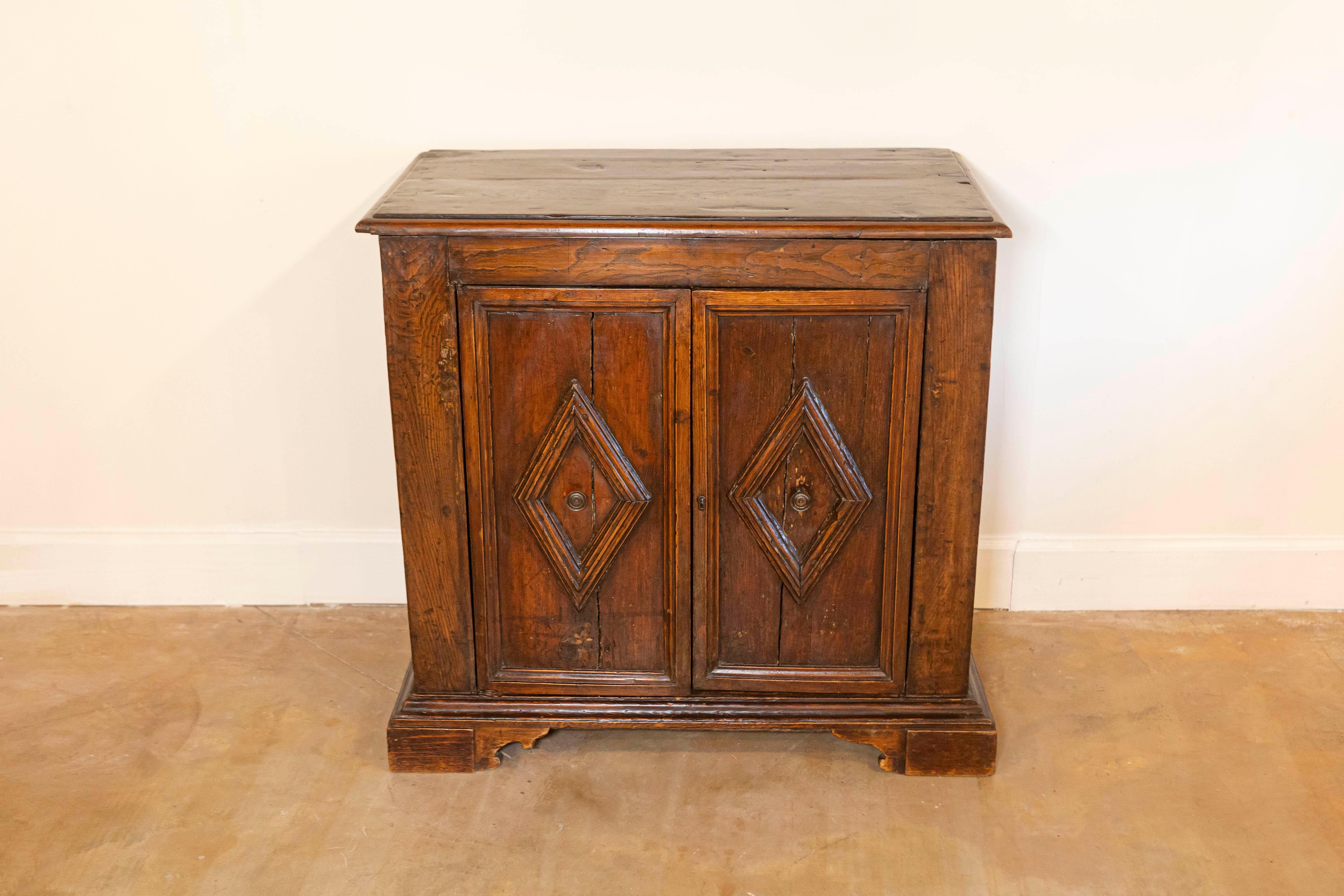 Bufé italiano de nogal de hacia 1790 con dos puertas y motivos romboidales tallados. Abraza la belleza intemporal y la rica herencia de este bufé italiano de nogal de hacia 1790, una obra maestra de la artesanía y el diseño de finales del siglo