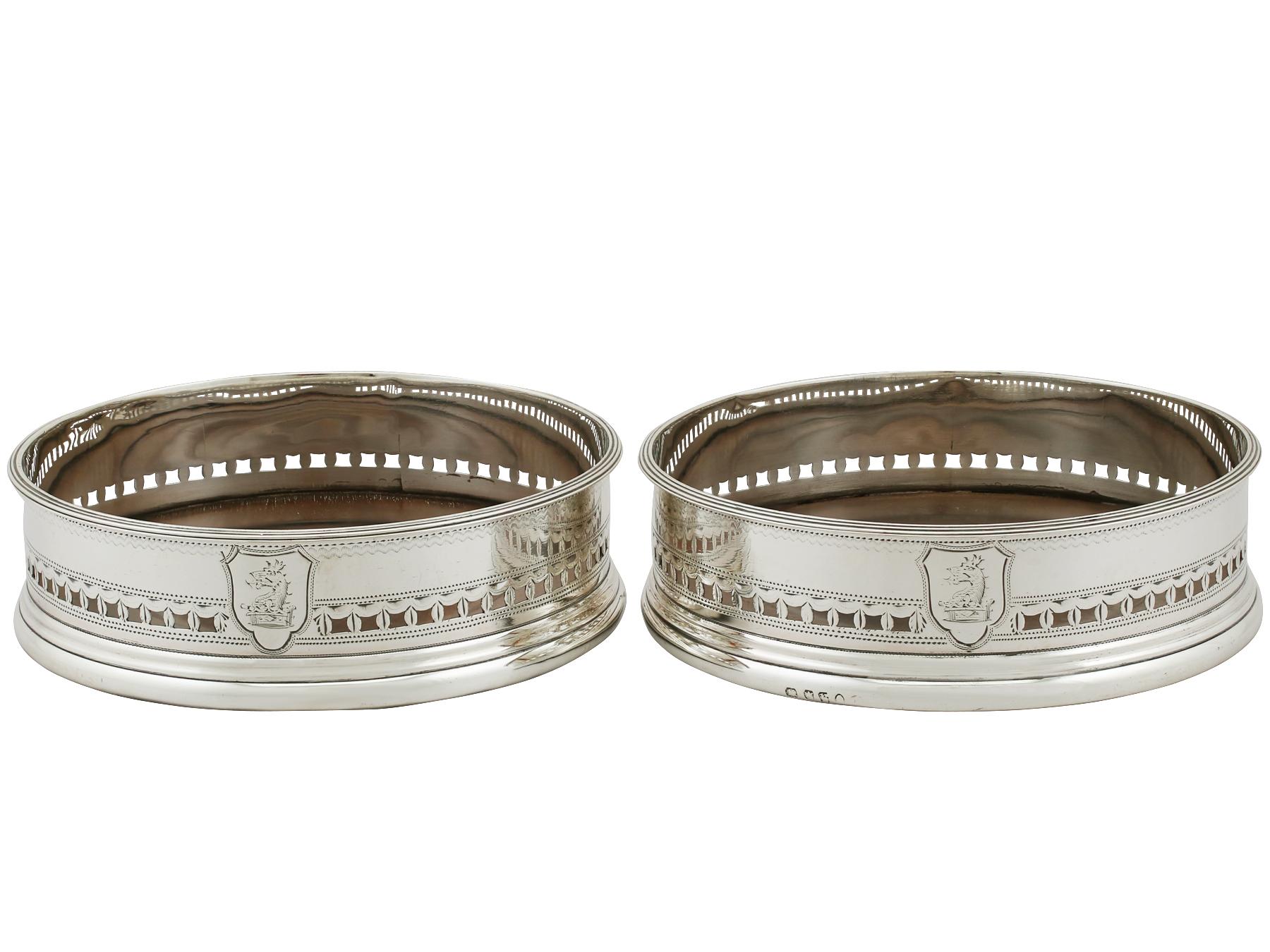 An exceptional, fine and impressive pair of antique Georgian English sterling silver and mahogany wood coasters.

These antique George III sterling silver coasters have a plain cylindrical form.

The surface of each coaster is embellished with a