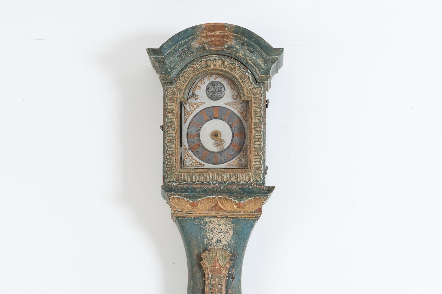 Long case clock manufactured by Sven Hansson-Berglin in 1797. Manufactured in northern Sweden in the county of Jämtland. The clock is richly decorated with intricate wooden carvings. The door in front of the clock face has old glass tinted green.