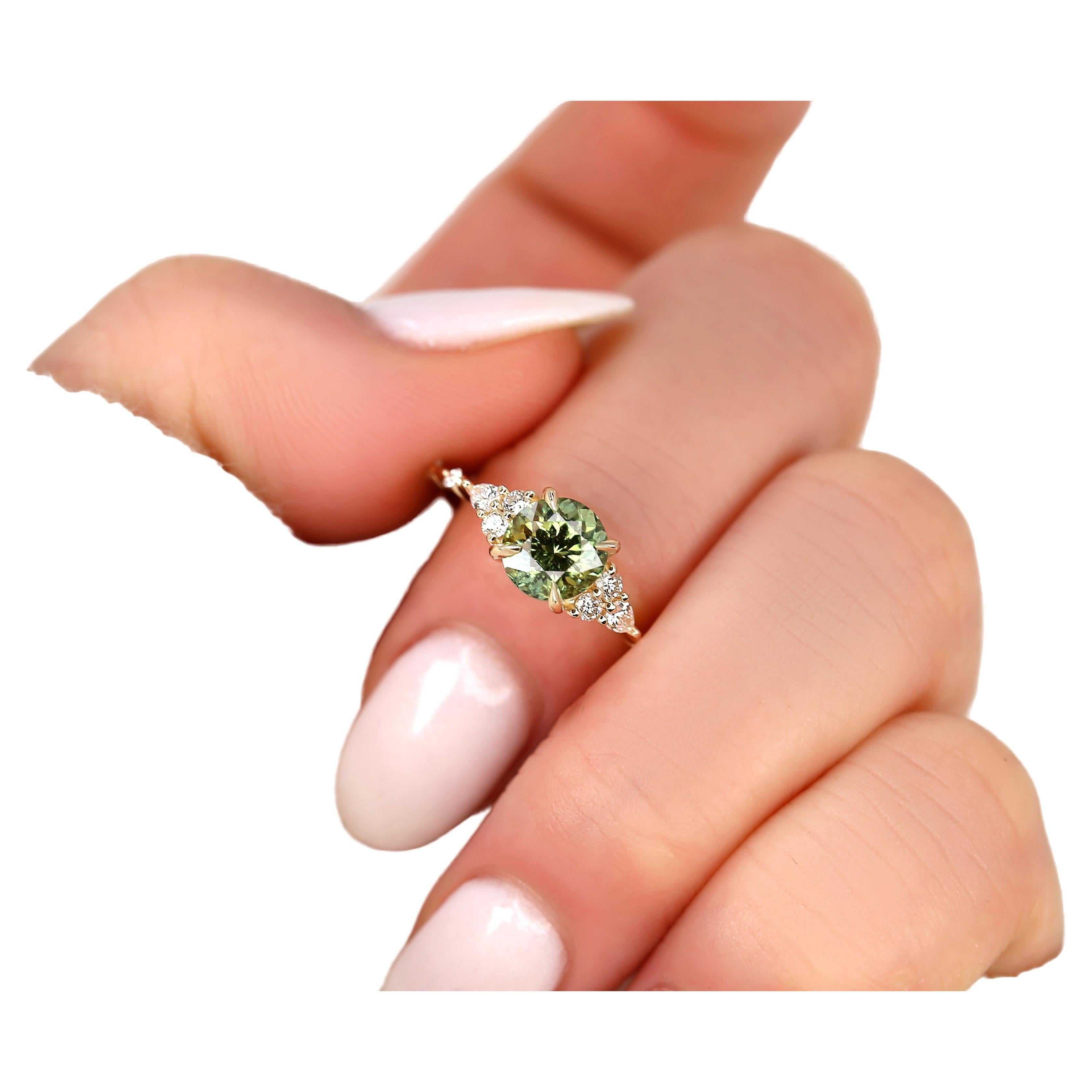 Entfesseln Sie die Romantik mit unserem zierlichen, runden Ring Anastasia, in dessen Mittelpunkt ein bezaubernder, blaugrüner Saphir steht, der von zarten Diamanten umgeben ist. Ein Design, bei dem jedes Funkeln eine Geschichte von Liebe und Eleganz