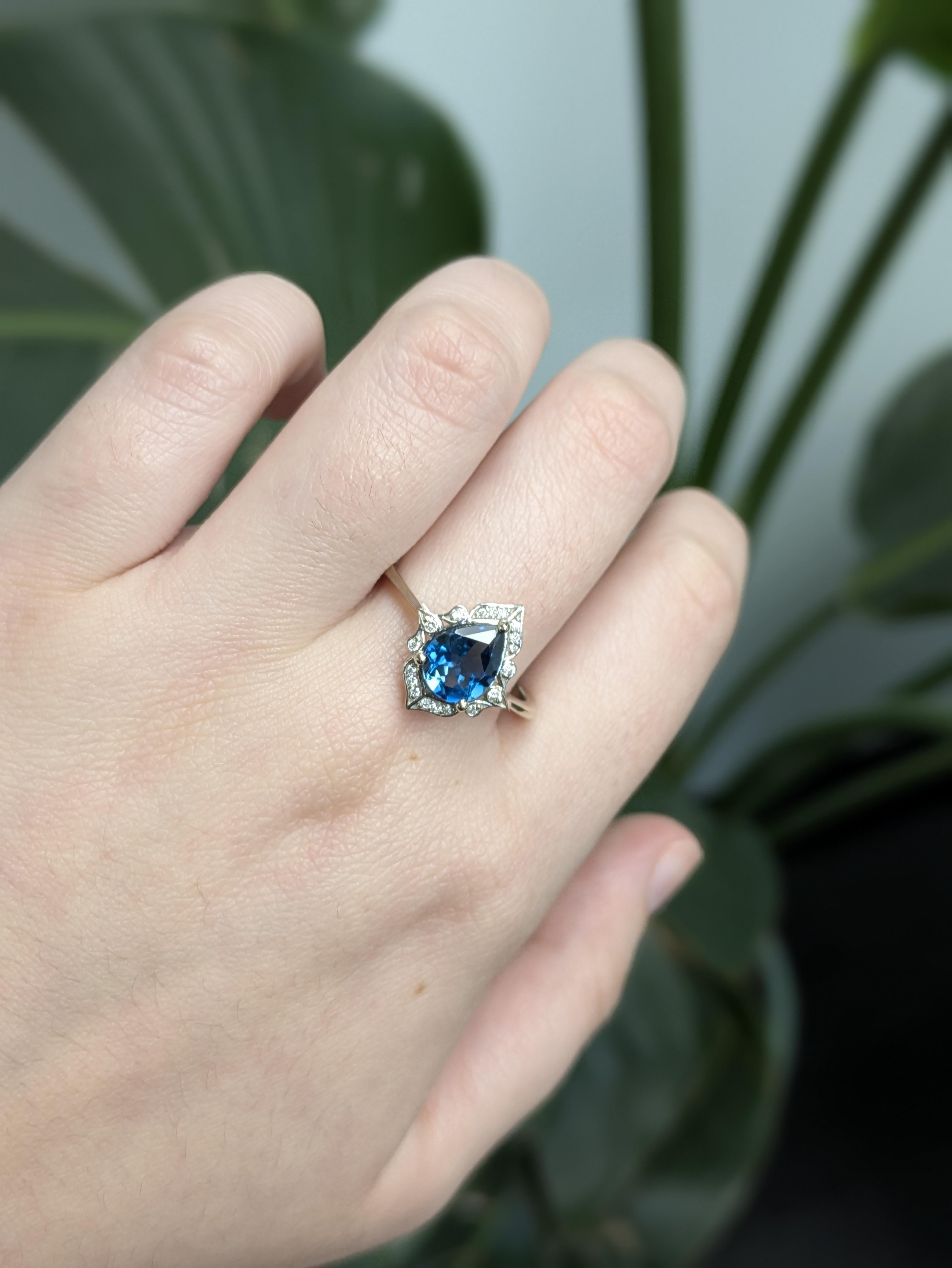 Fai una dichiarazione elegante e lunatica con questo affascinante anello con un topazio blu di Londra a forma di pera, incastonato in oro bianco massiccio 14 carati. Circondata da scintillanti accenti di diamanti rotondi naturali, la pietra centrale