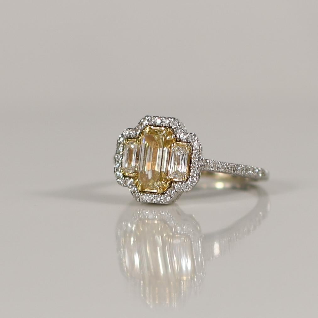 Elevate your love story with this modern masterpiece of sophistication and style – a three-stone engagement ring that exudes contemporary elegance. At its center shines a mesmerizing 1.03 carat fancy light yellow diamond, cut to perfection in an